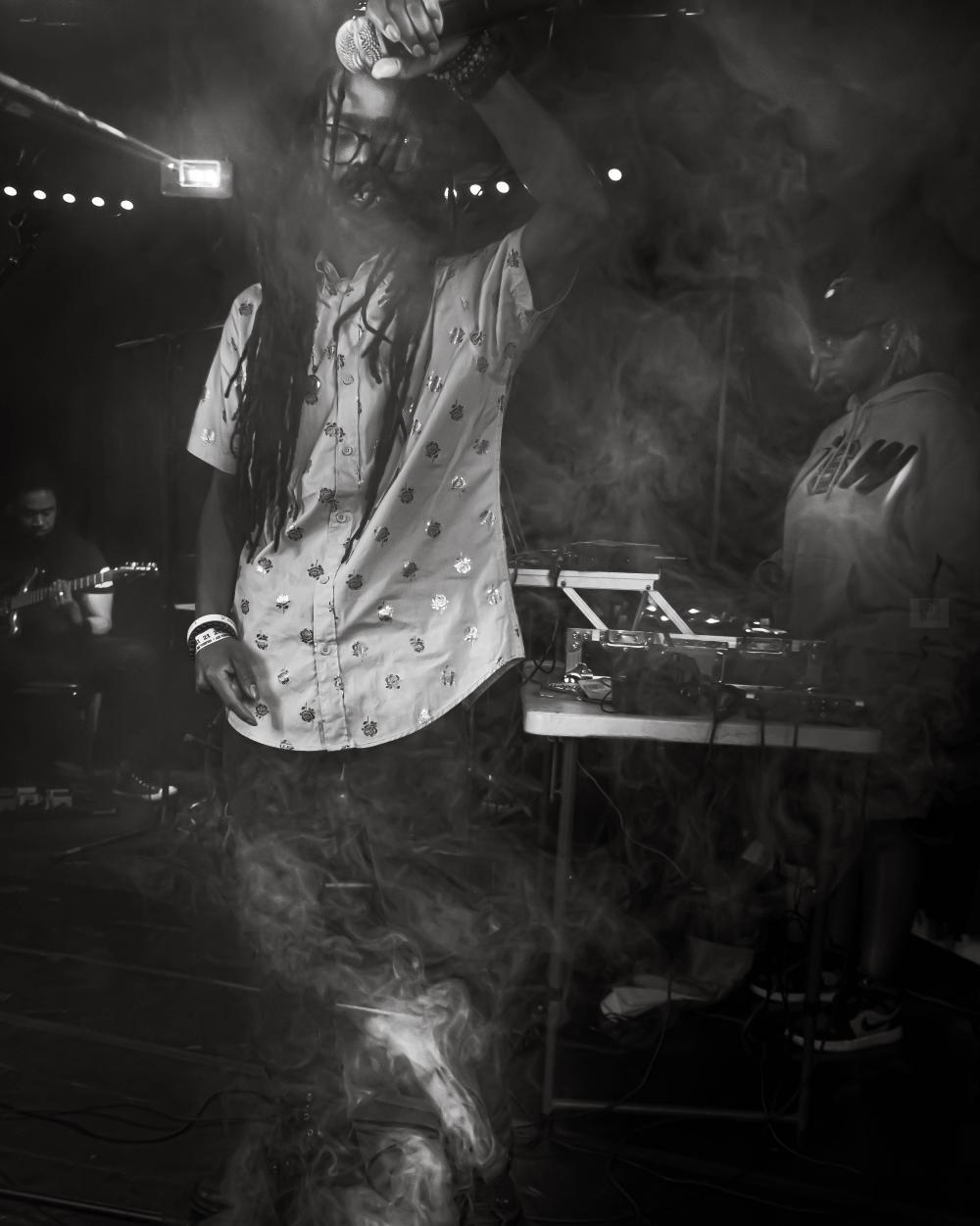 a man with dreadlocks standing in front of a microphone