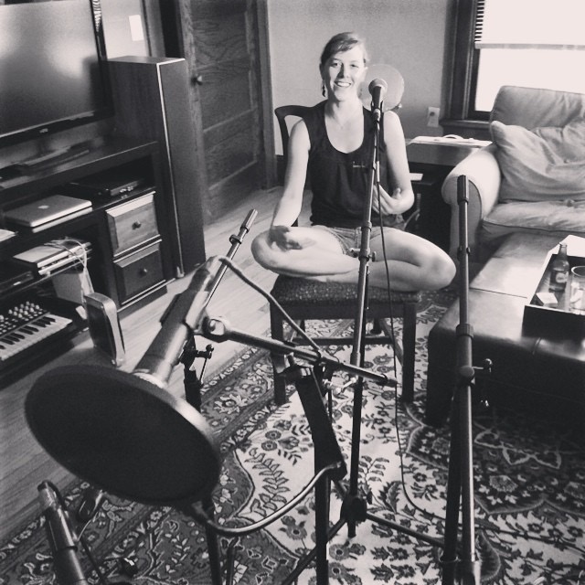 a woman sits in front of a microphone in a living room