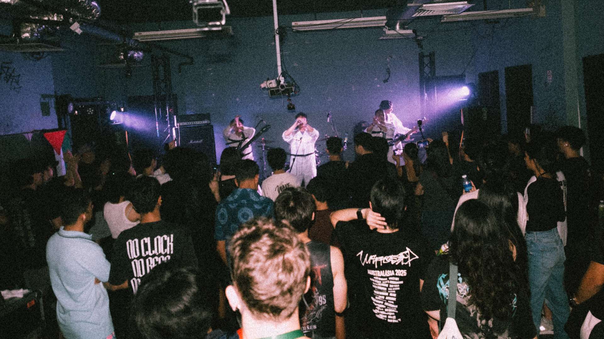 a crowd of people watching a band perform in a dark room