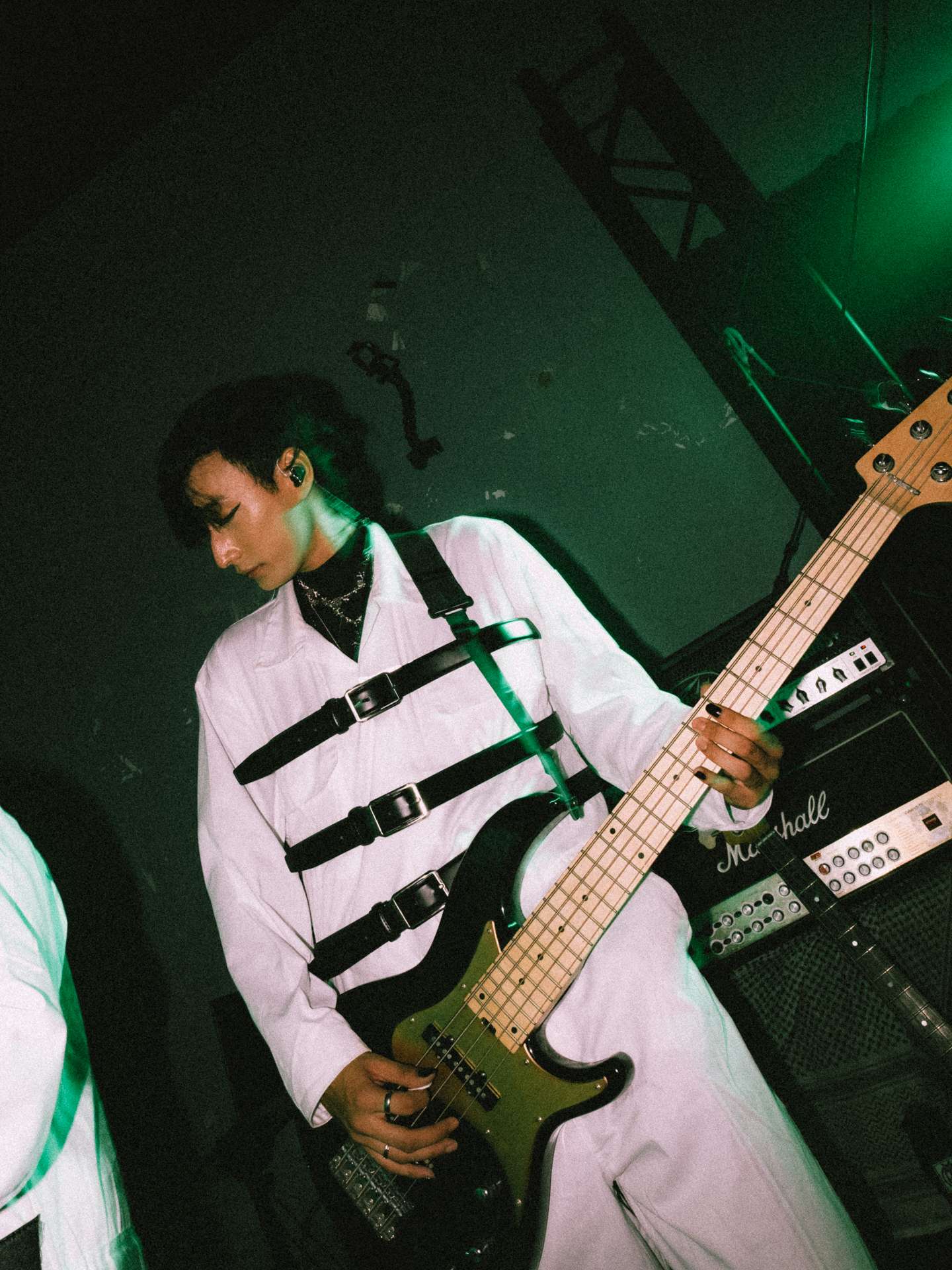 a man in a white suit holding a bass guitar