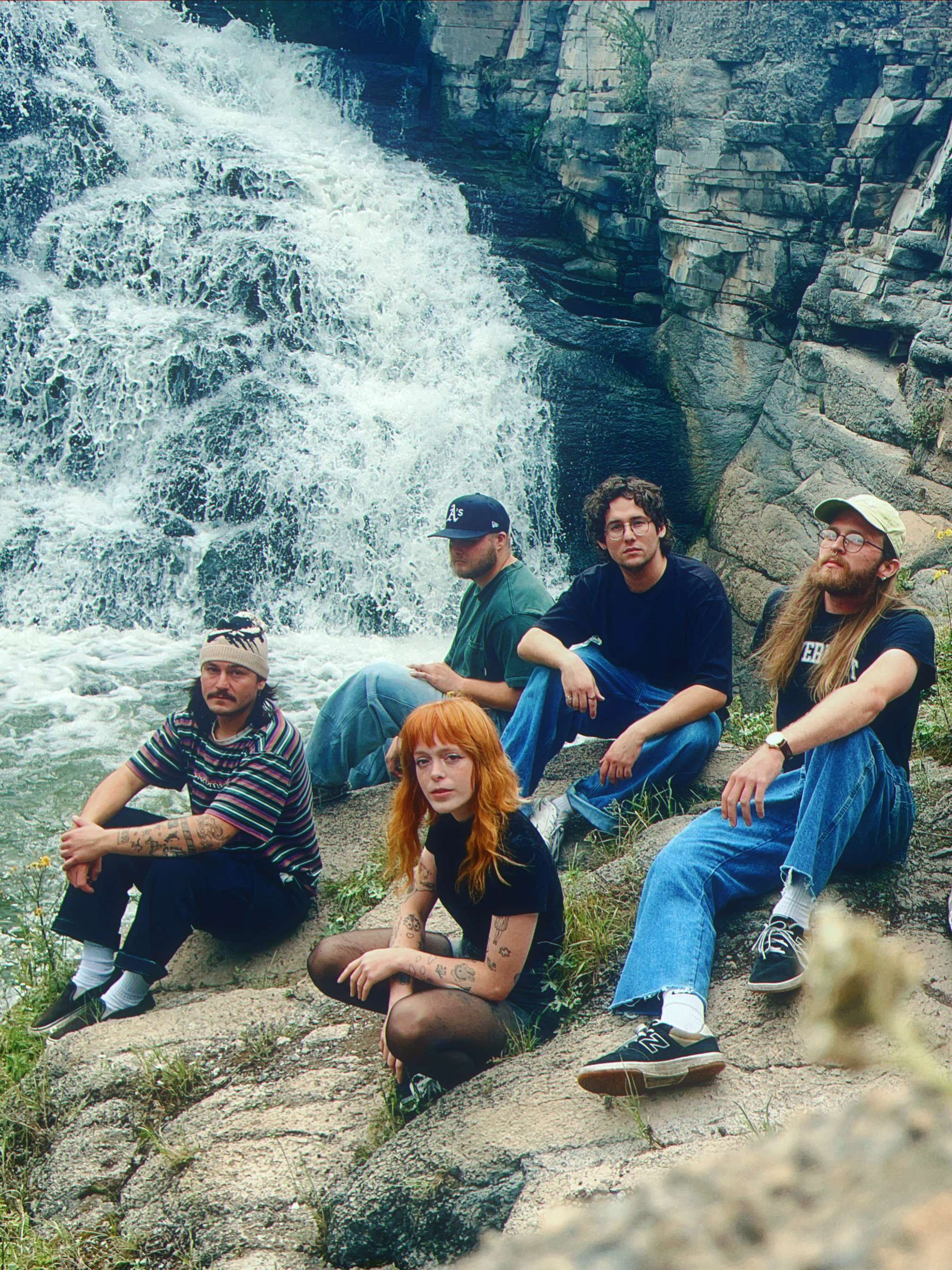 a group of people sitting on rocks next to a waterfall