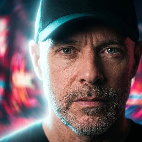 a man wearing a baseball cap in front of a neon background