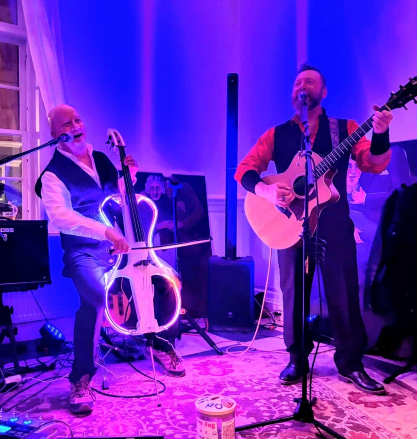 two men playing music in a room with blue lights