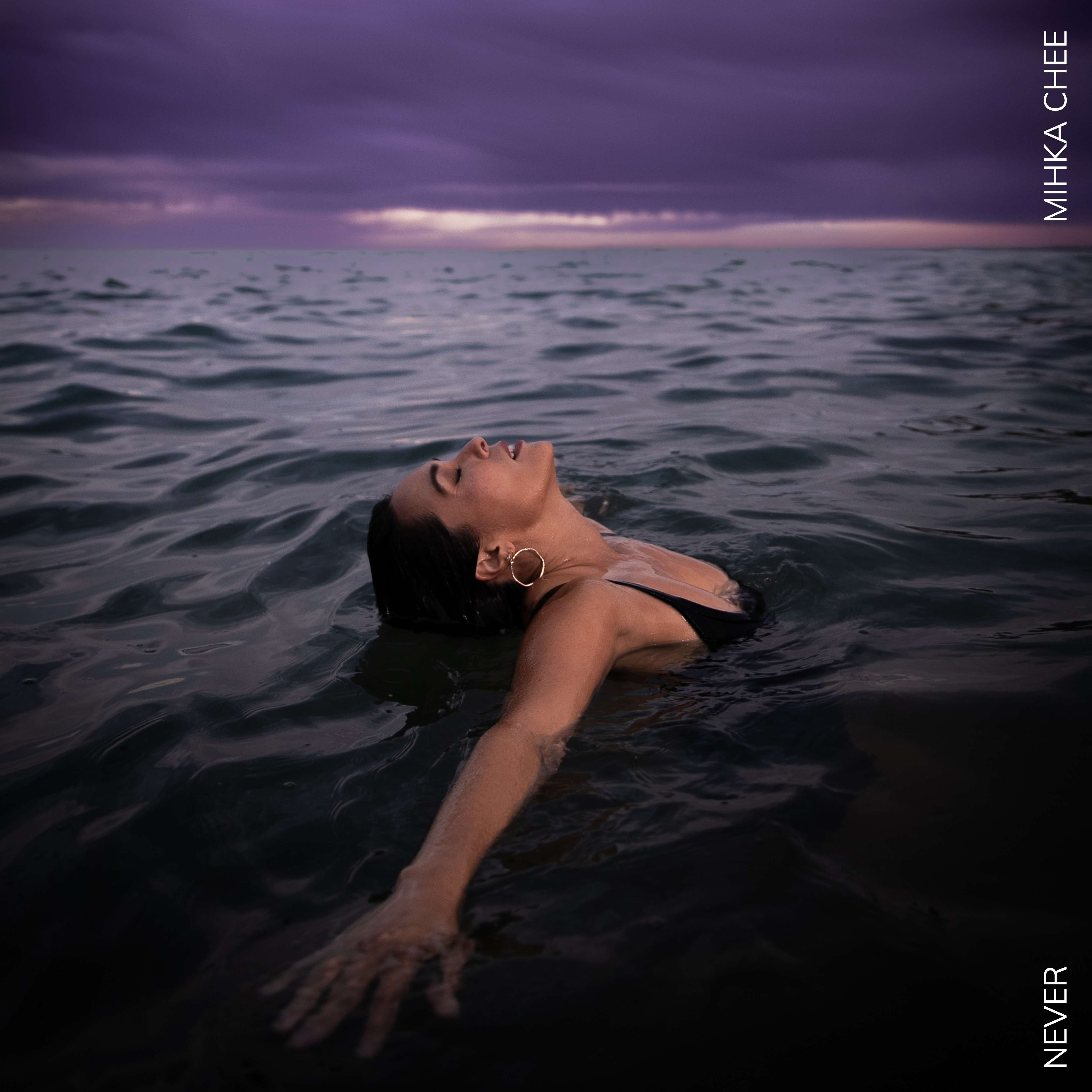 Mihka Chee - Never: a woman floating in the ocean with her arms outstretched
