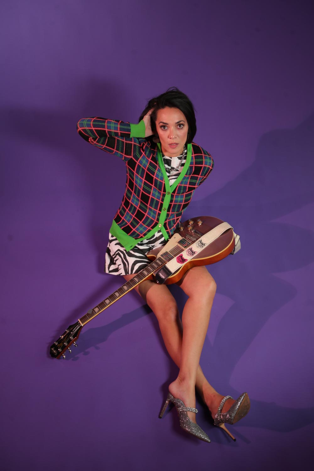 a woman posing with a guitar on a purple background