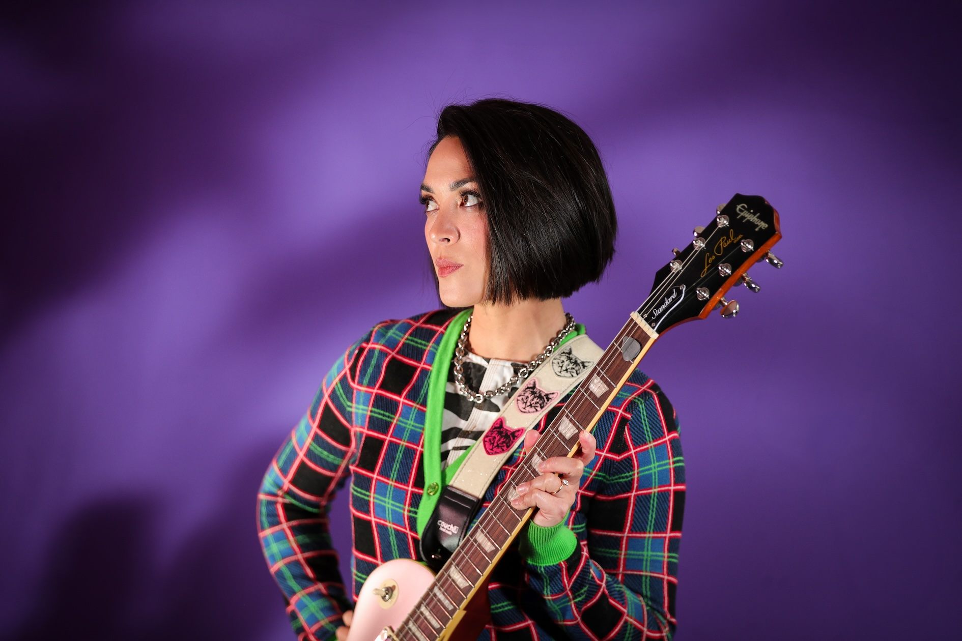 a woman holding a guitar in front of a purple background