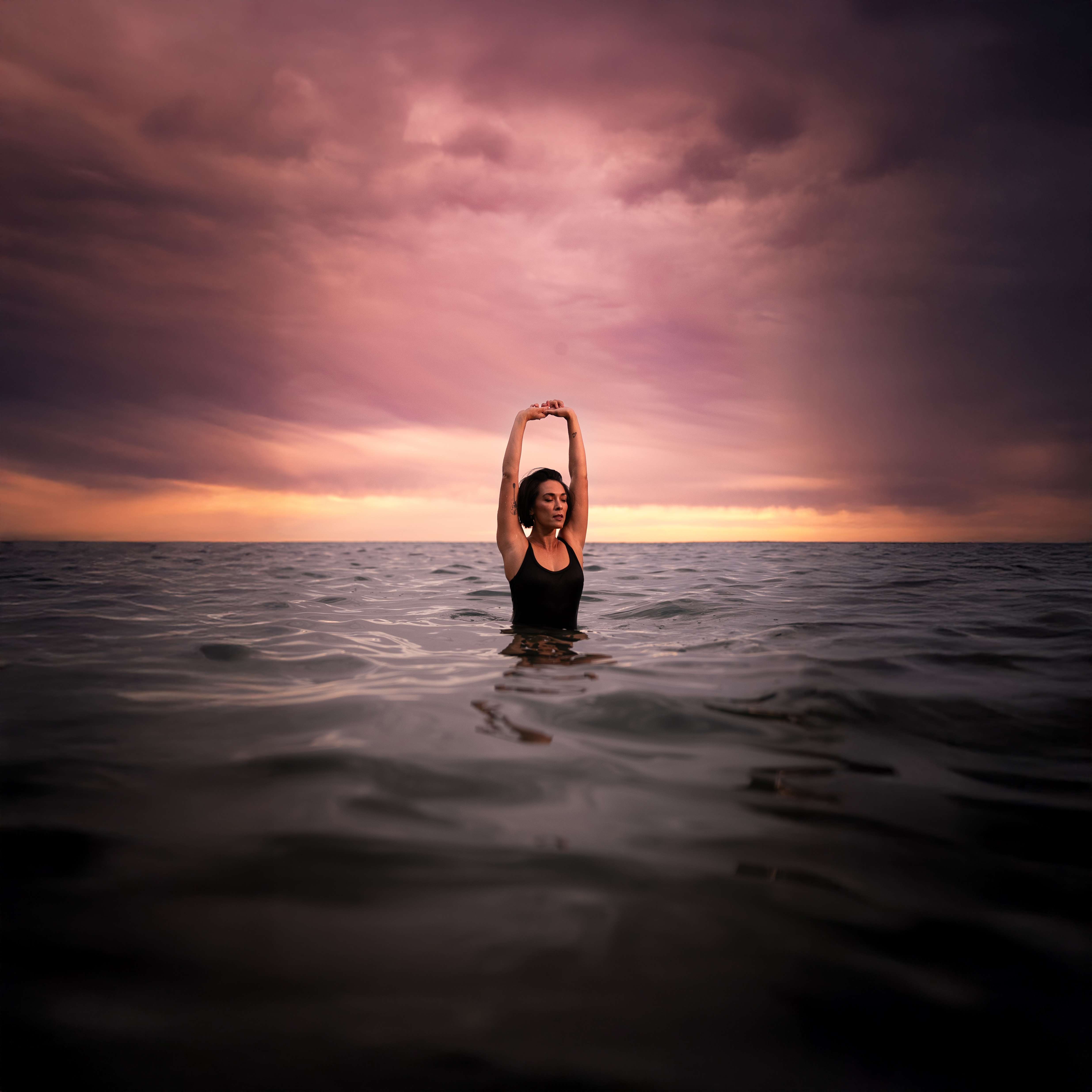 a woman in the ocean with her arms outstretched