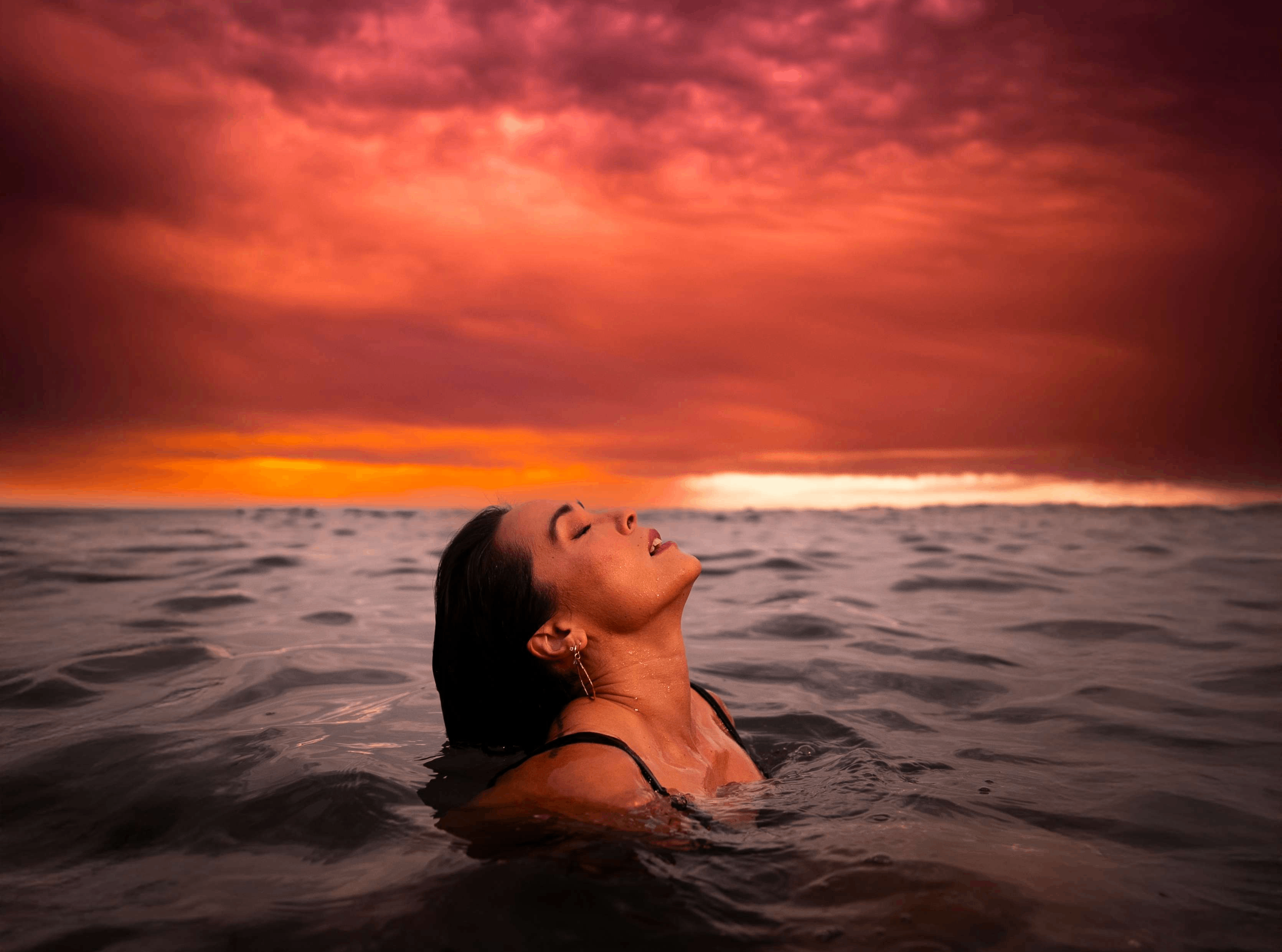 a woman swimming in the ocean at sunset