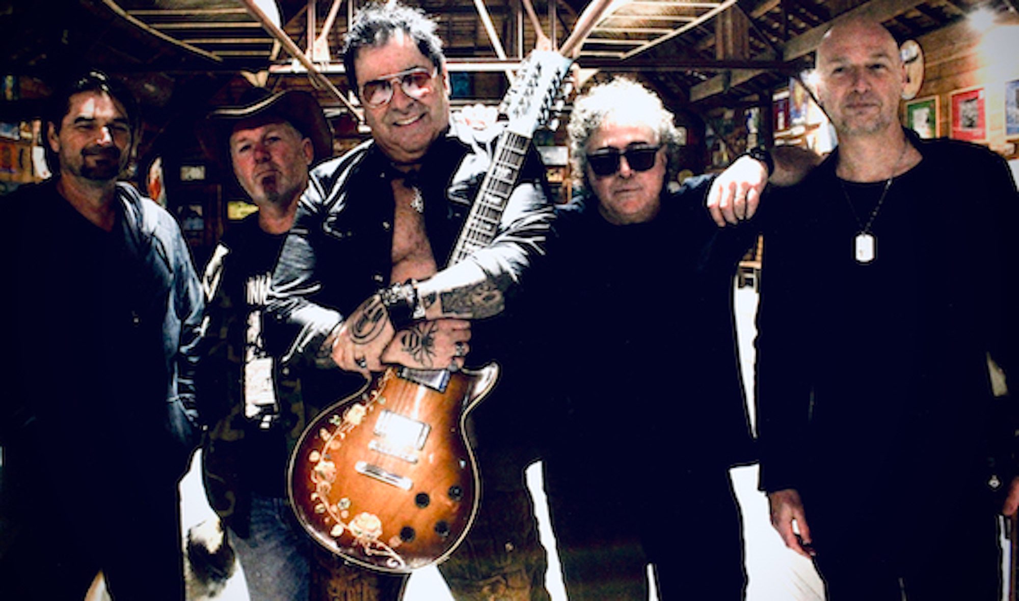 a group of men posing for a picture with a guitar