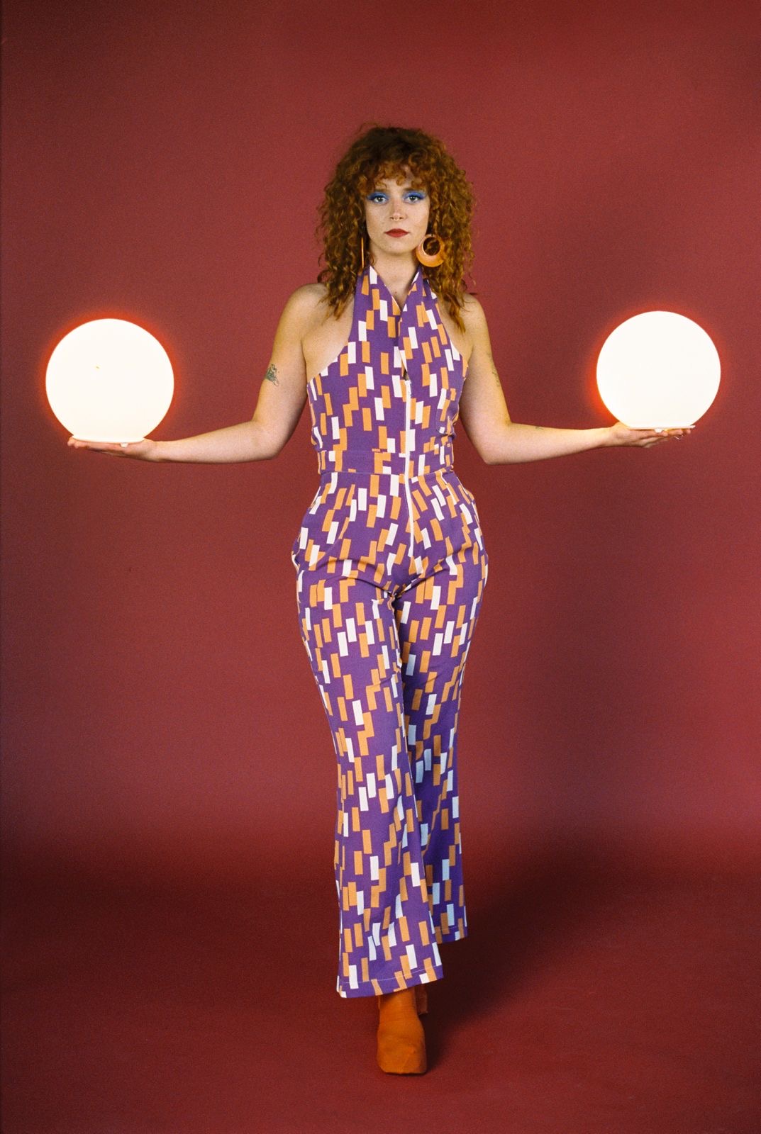 a woman in a purple jumpsuit holding two balls