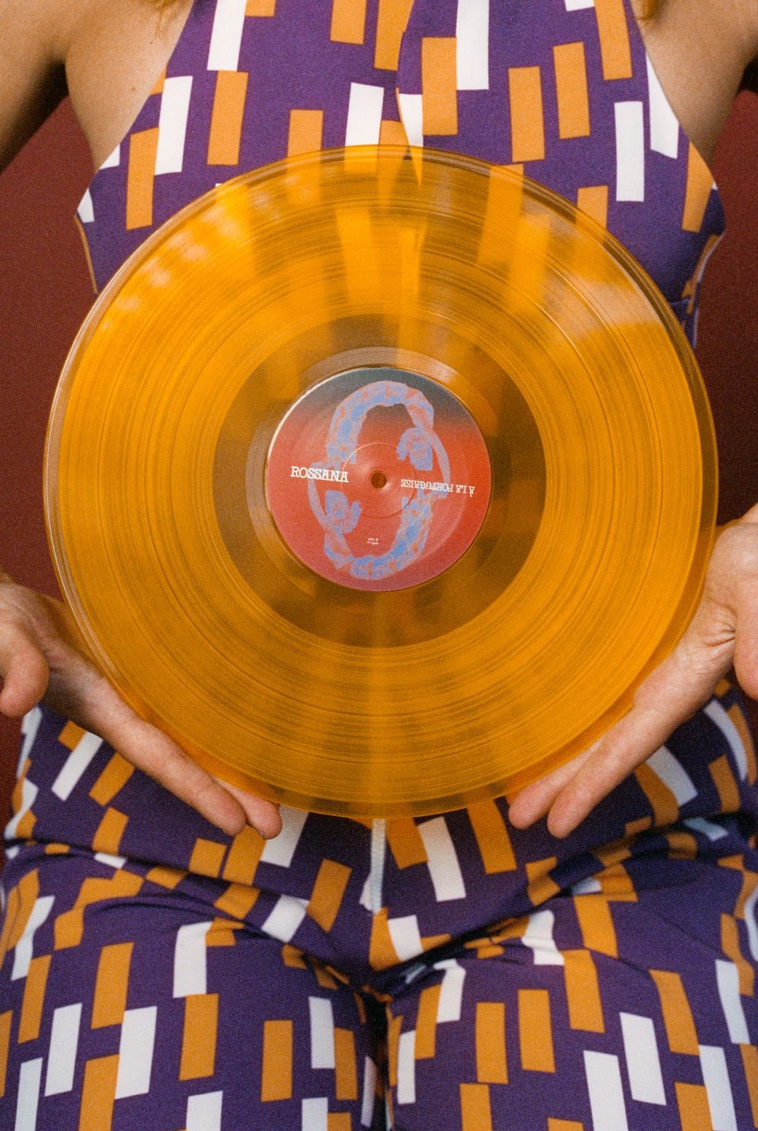 a woman holding an orange vinyl record