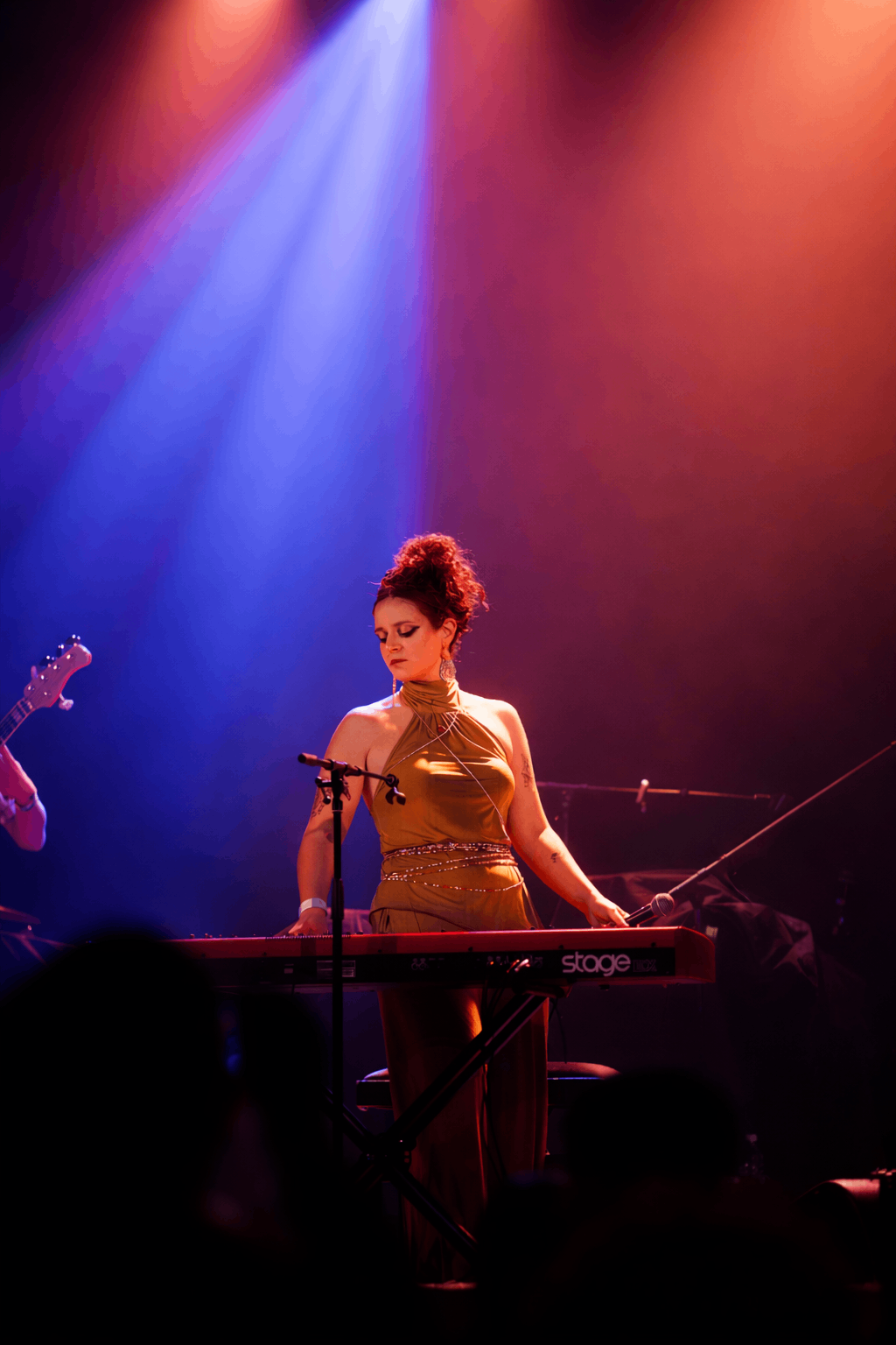 a woman in a gold dress is playing a keyboard on stage
