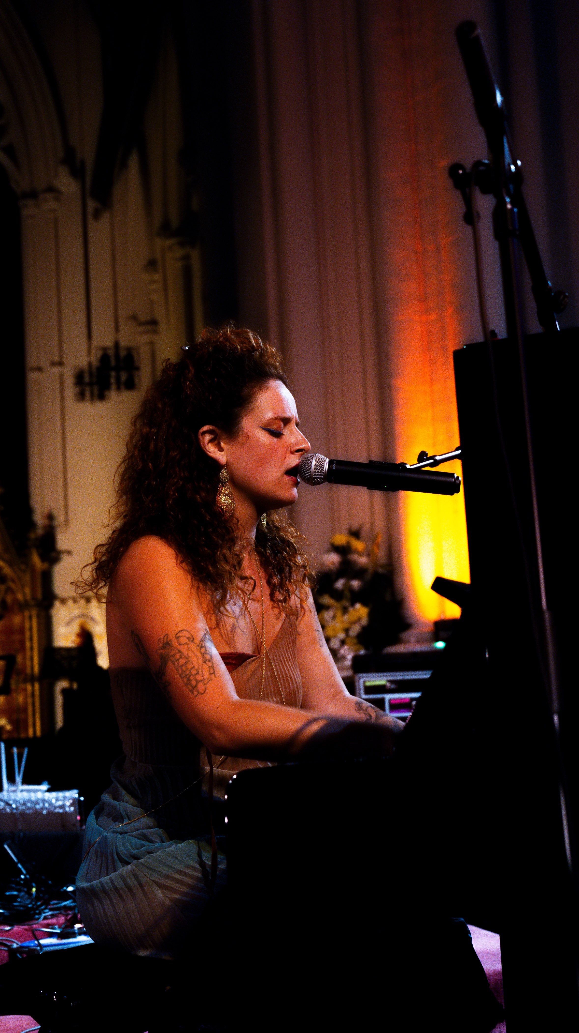 a woman playing a piano in front of a microphone