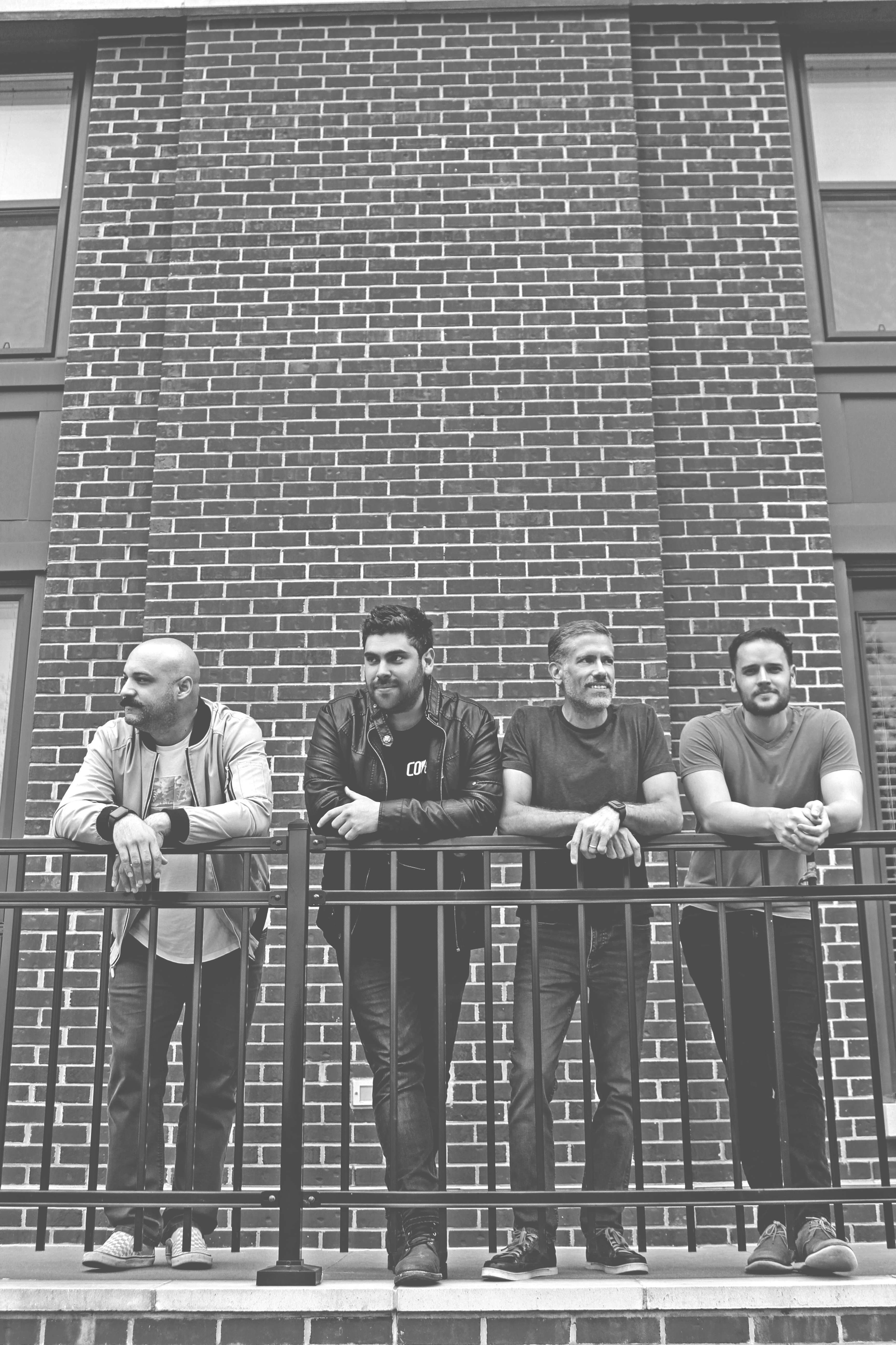 black and white photo of a group of men leaning on a railing