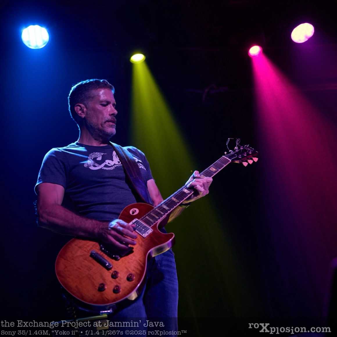 a man playing an electric guitar in front of colorful lights