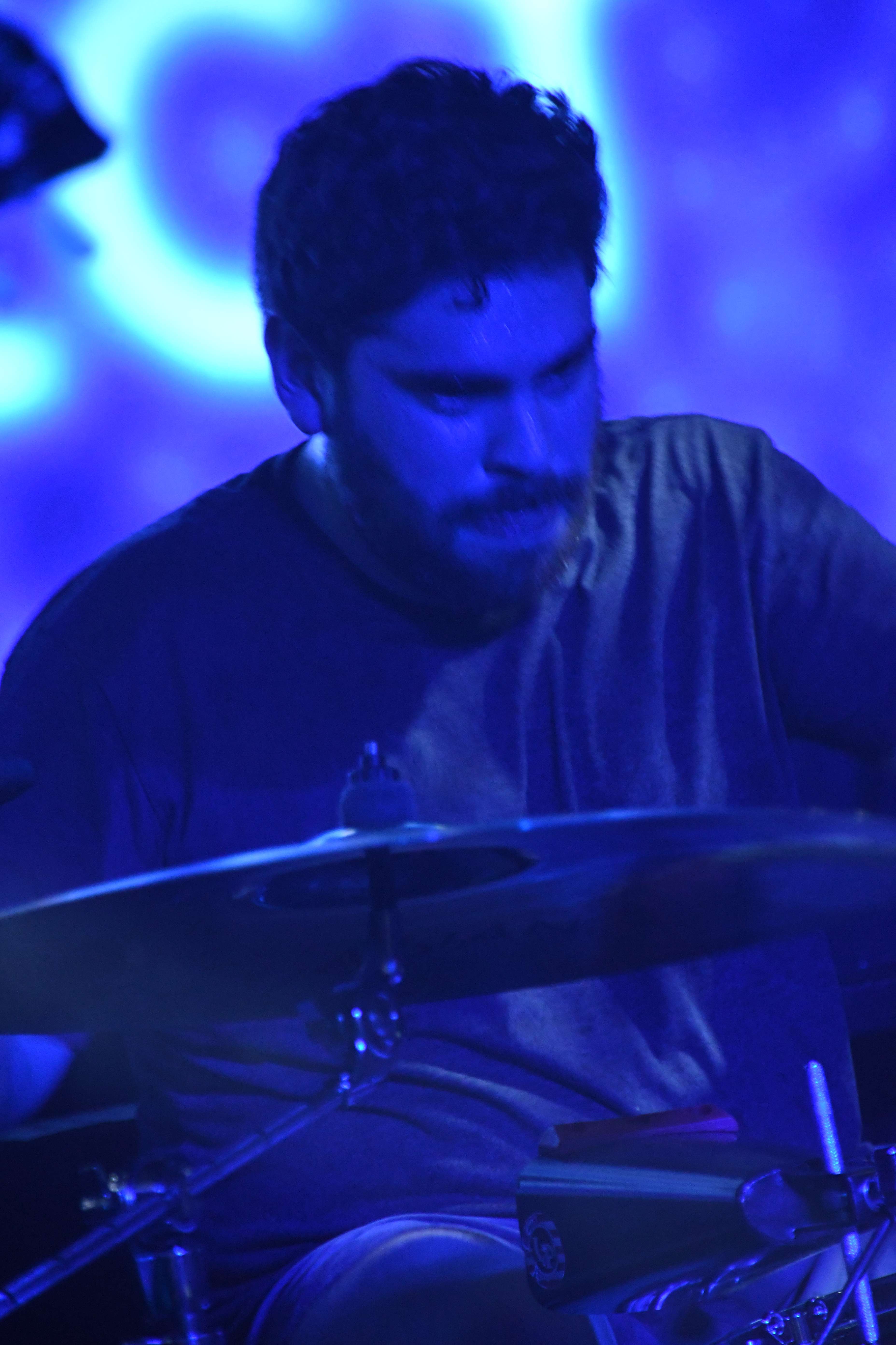 a man playing drums in front of a blue background
