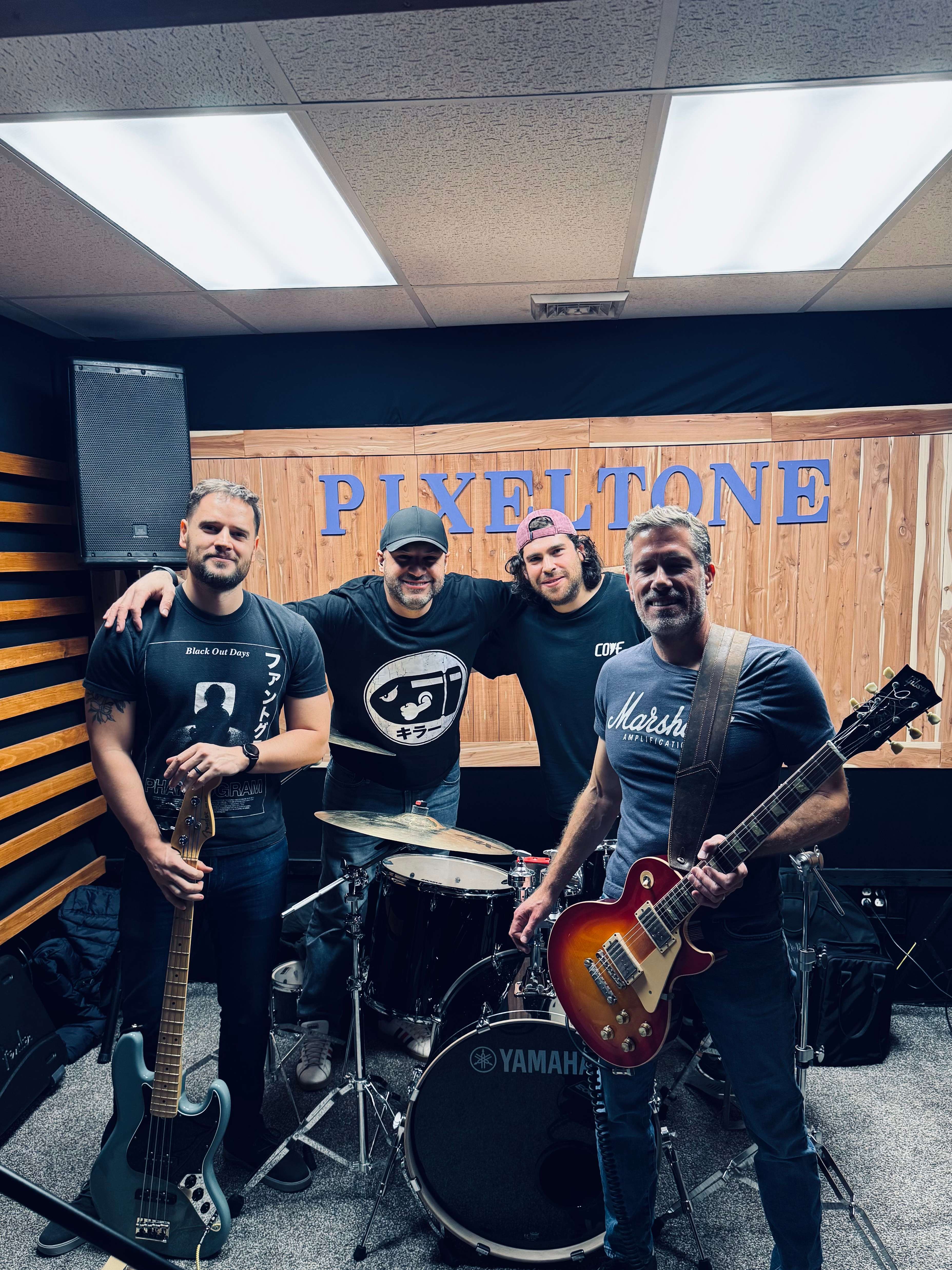 a group of men posing for a photo in a recording studio