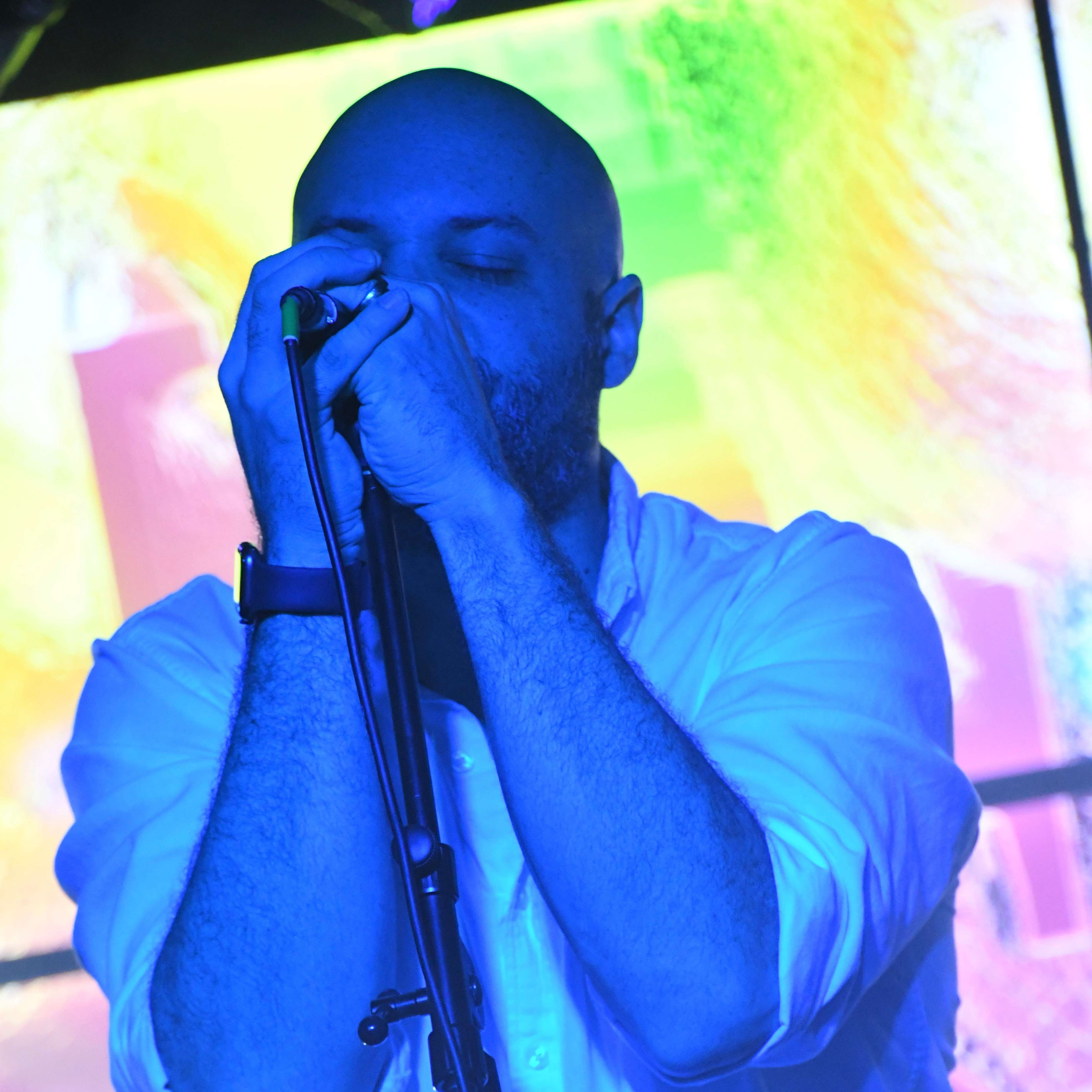 a bald man singing into a microphone