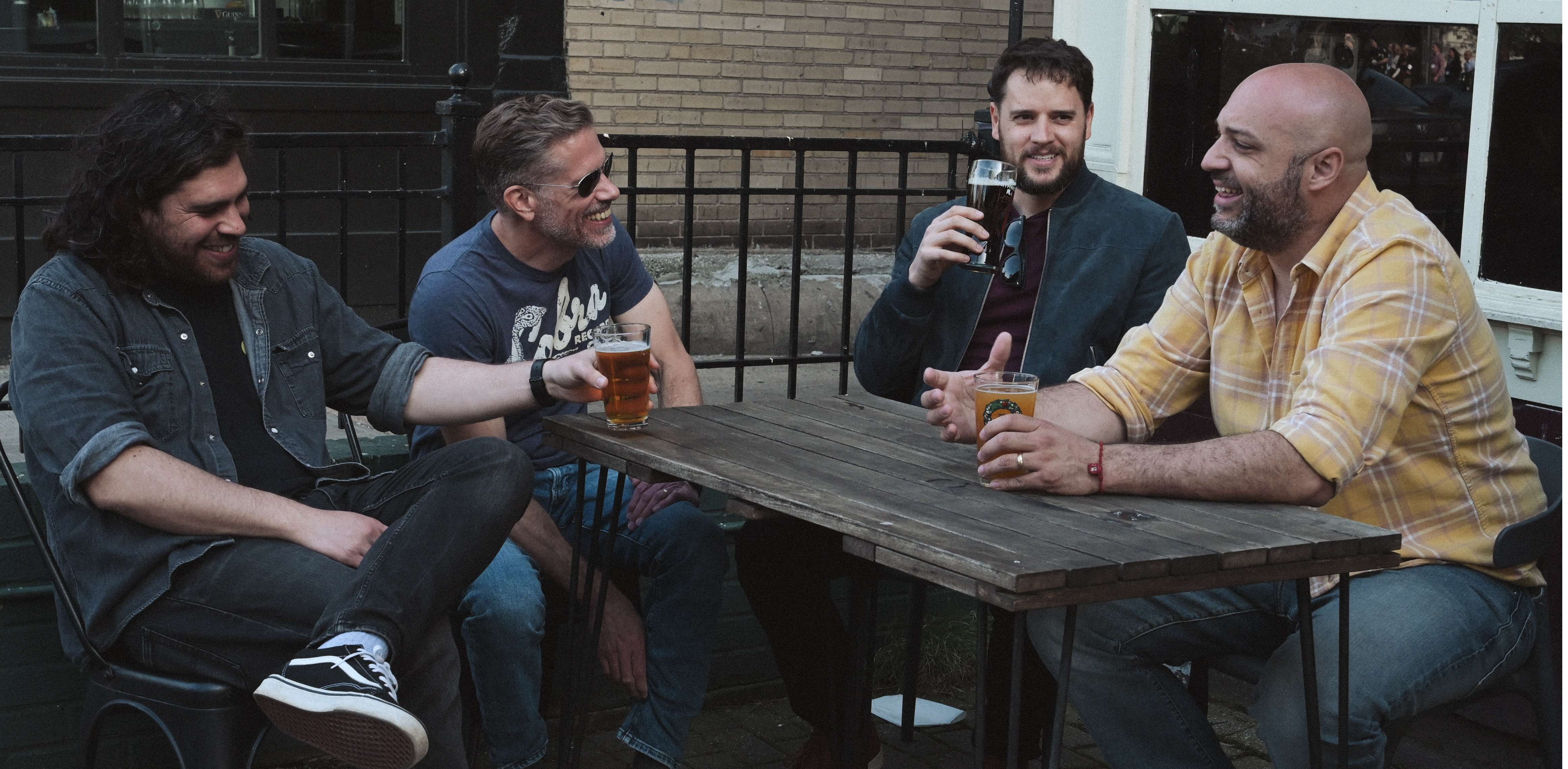 four men sitting at a table drinking beer