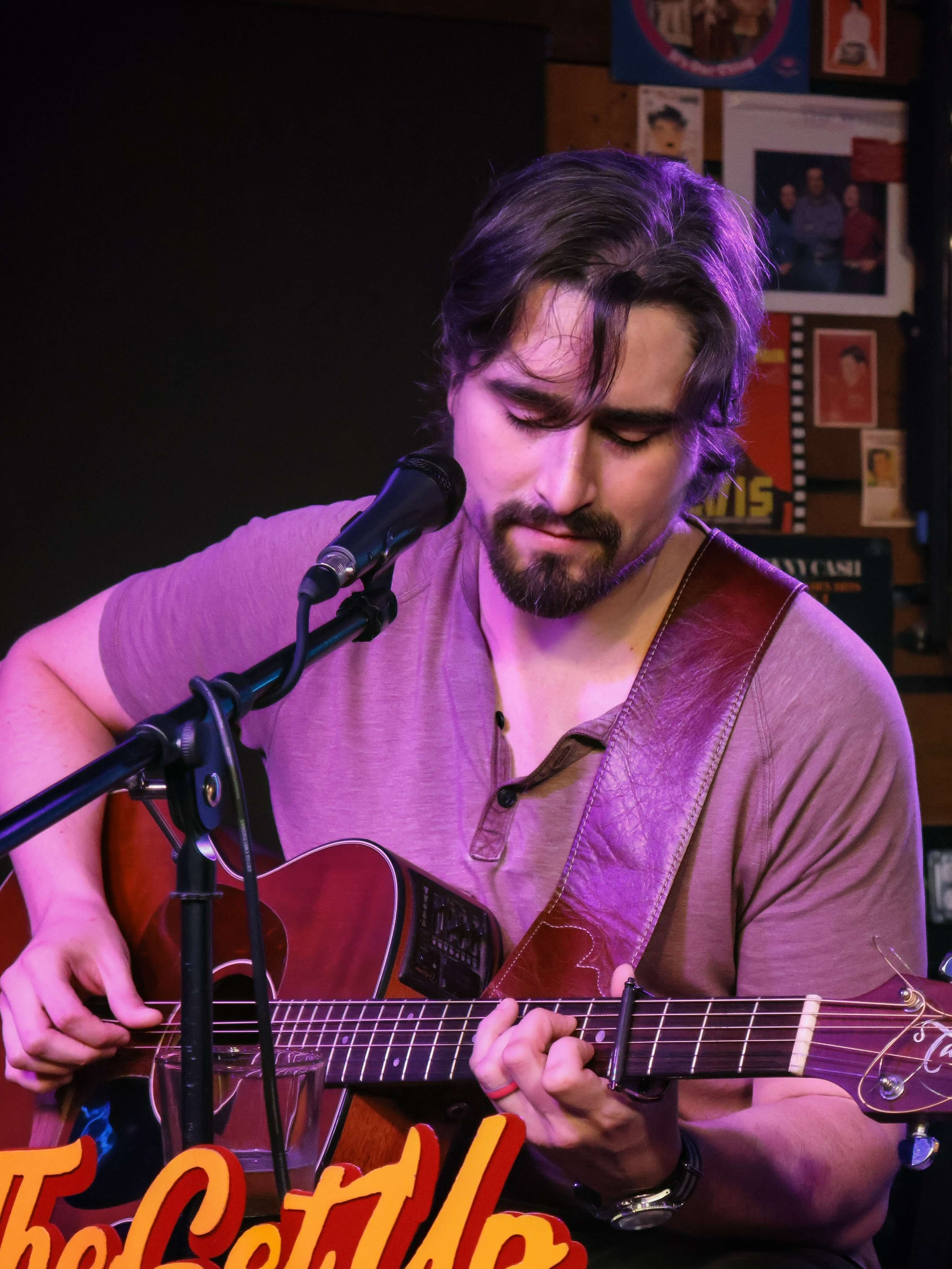 a man playing an acoustic guitar in front of a microphone