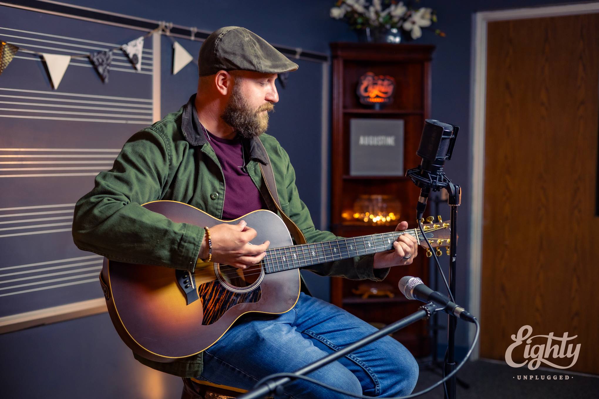 a bearded man playing an acoustic guitar in a recording studio