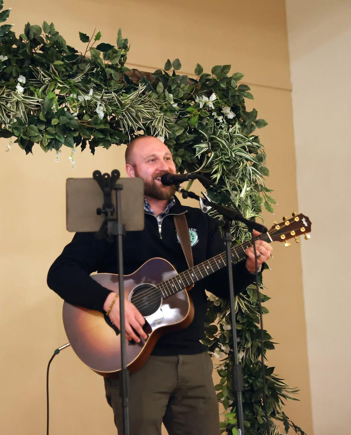 a man singing into a microphone with an acoustic guitar