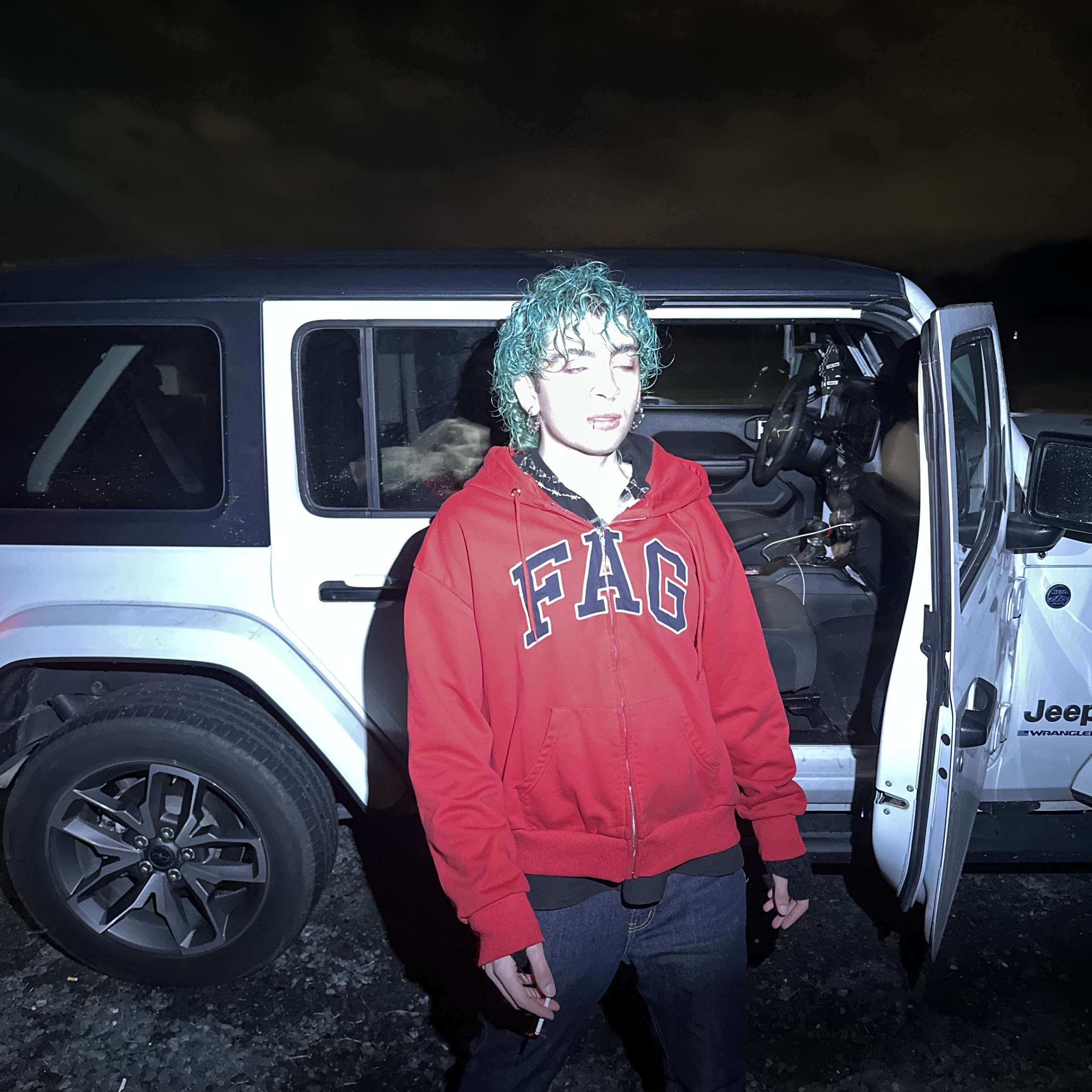 a man with green hair standing next to a jeep