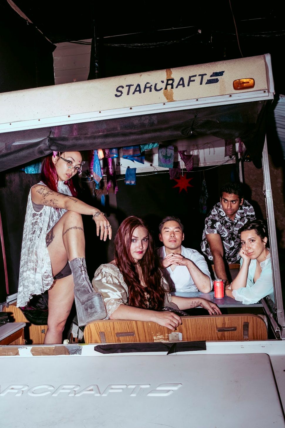 a group of people posing in the back of a camper van