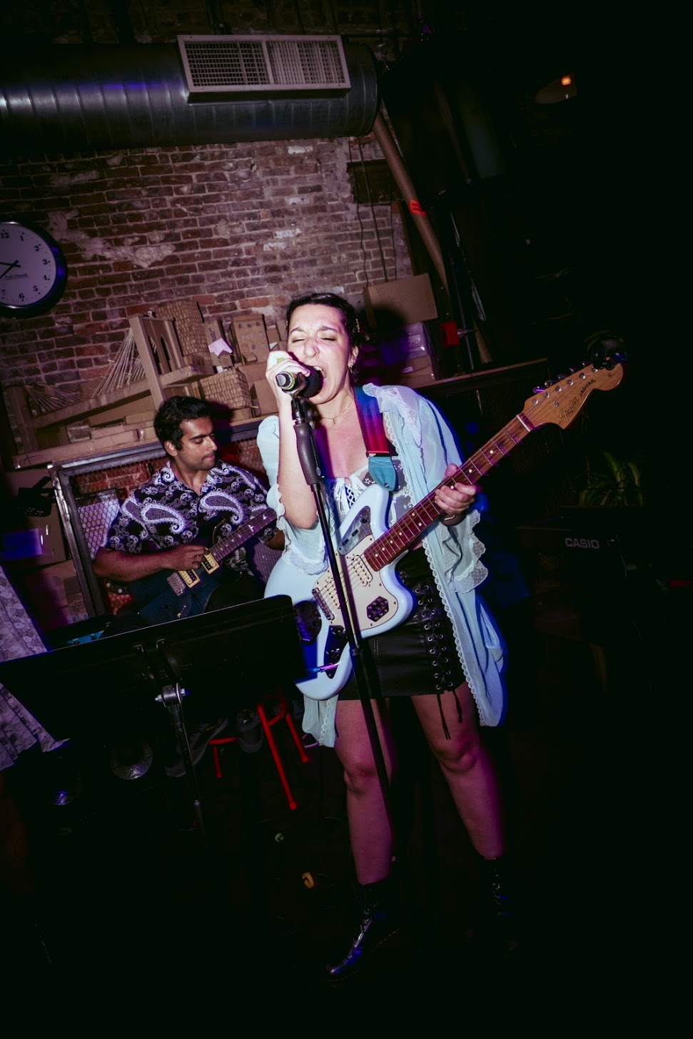 a woman singing with a guitar in front of a microphone