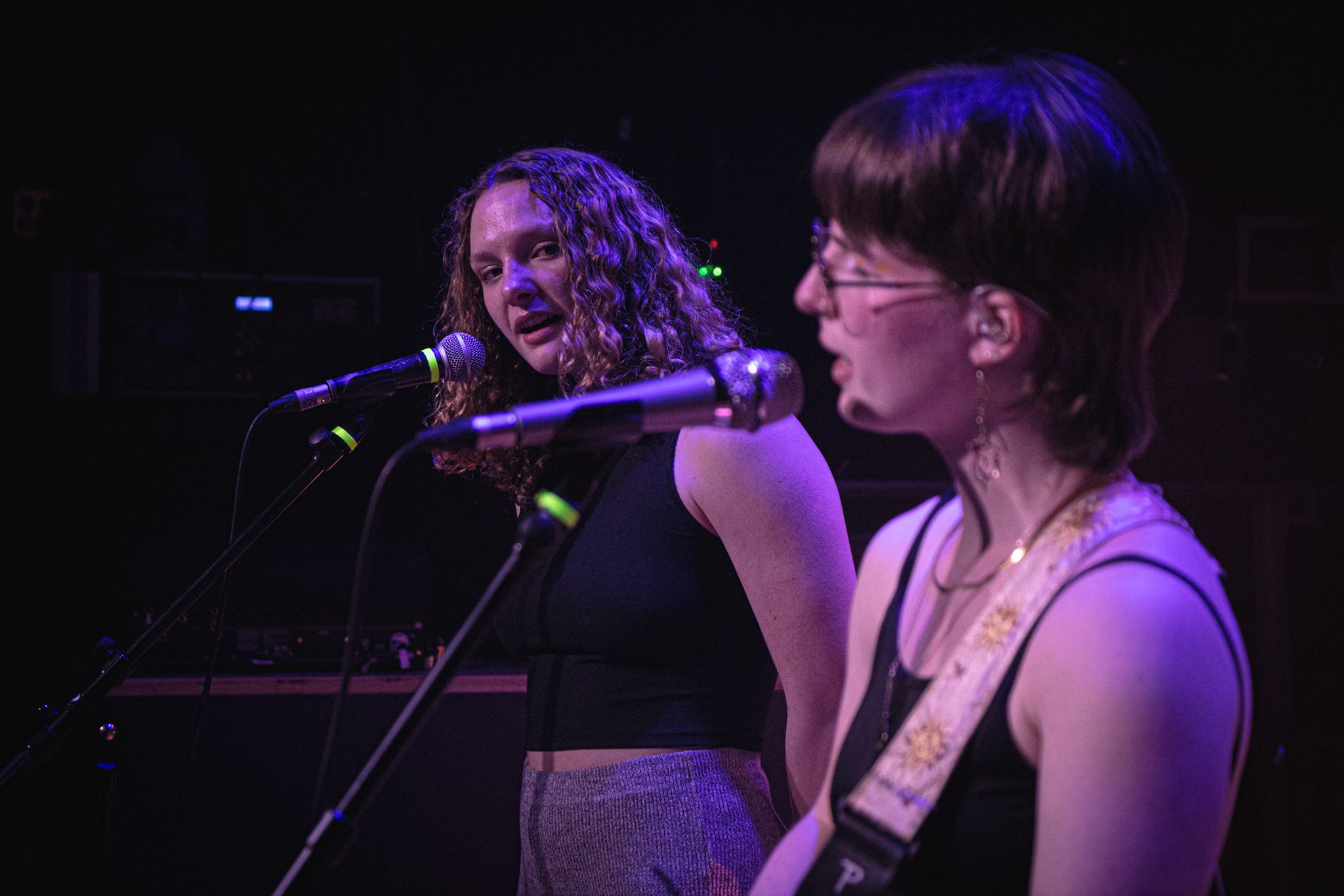 two women singing into microphones on stage