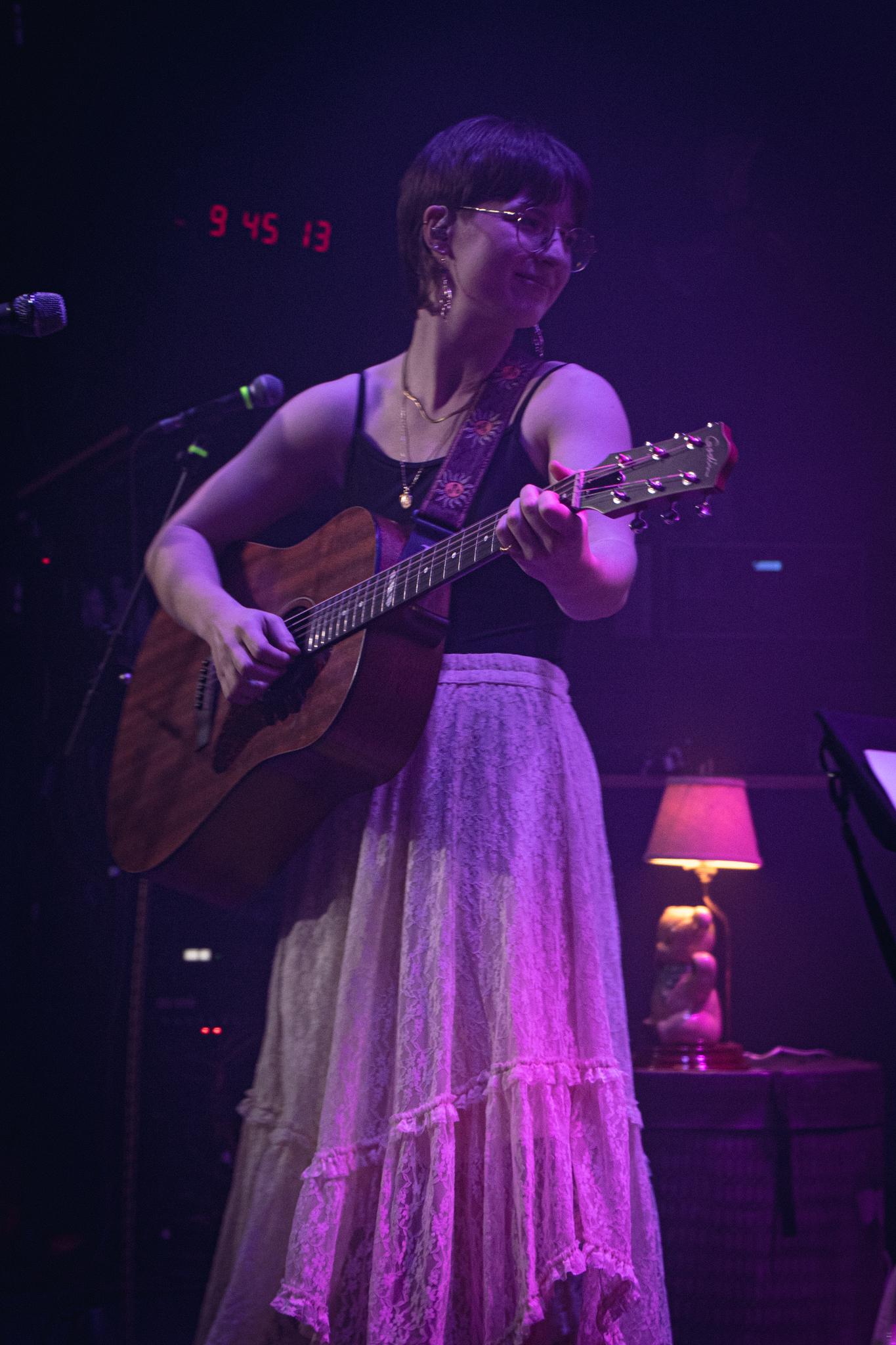 a woman playing an acoustic guitar on stage