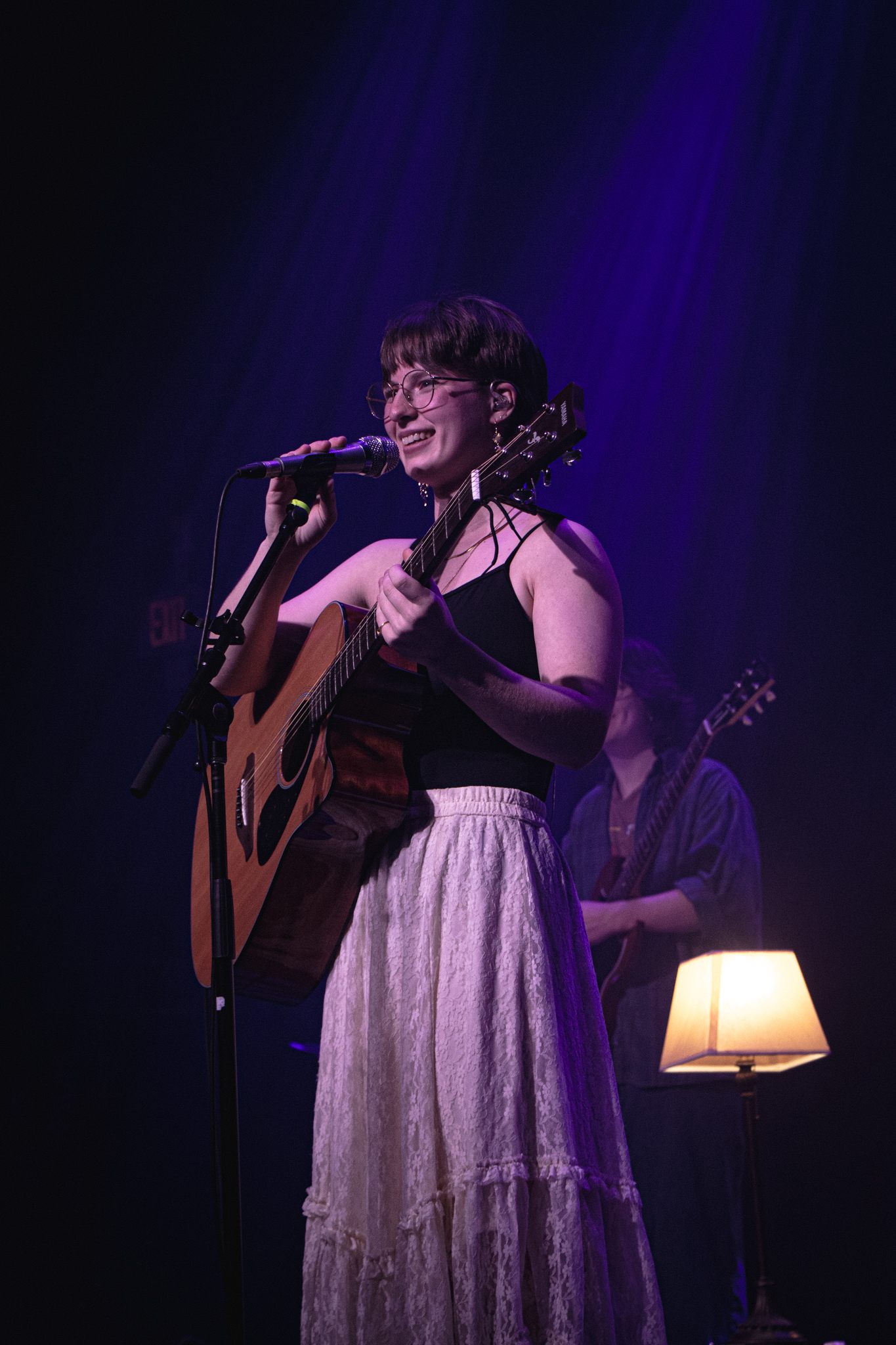 a woman playing an acoustic guitar on stage