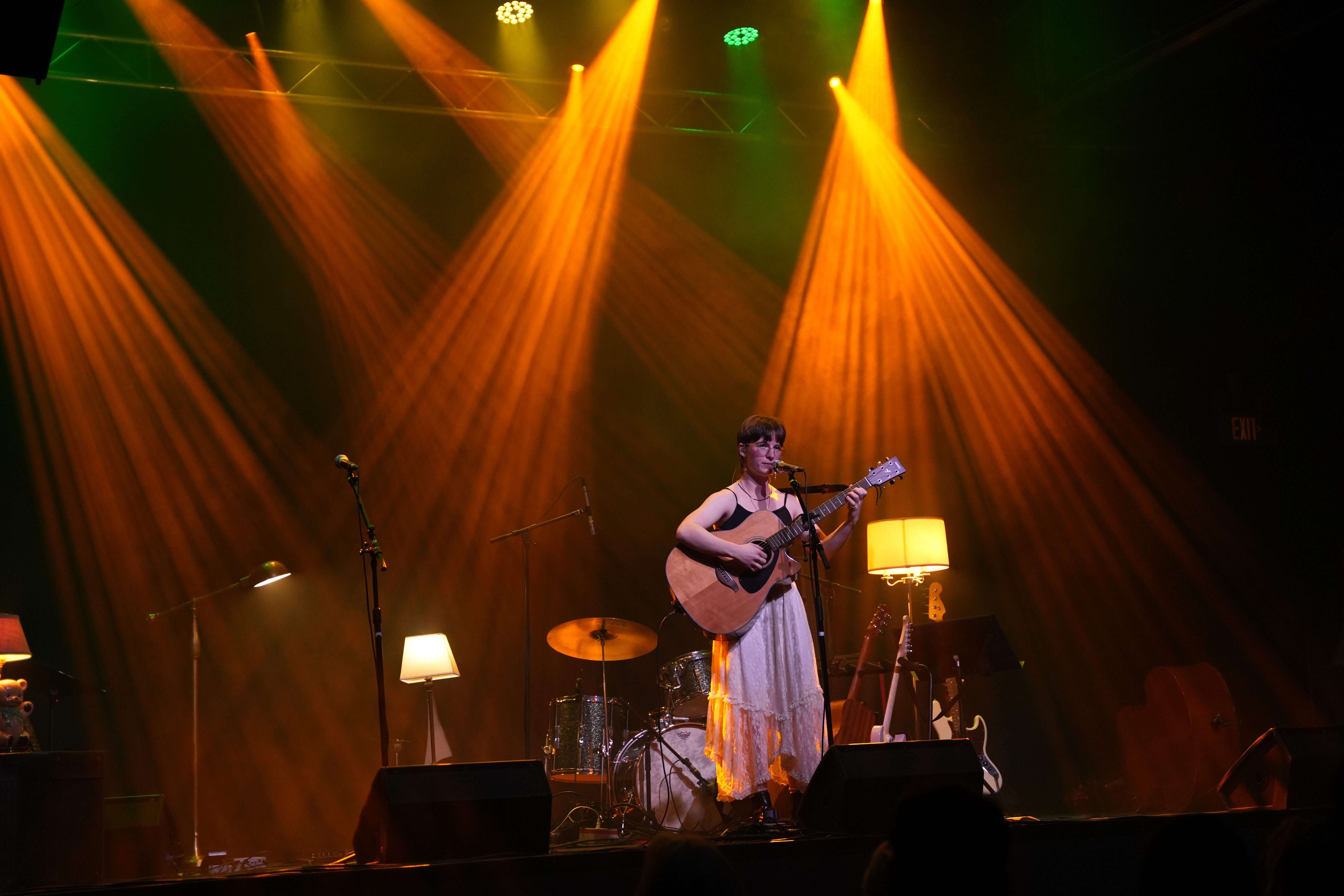a woman playing an acoustic guitar on stage