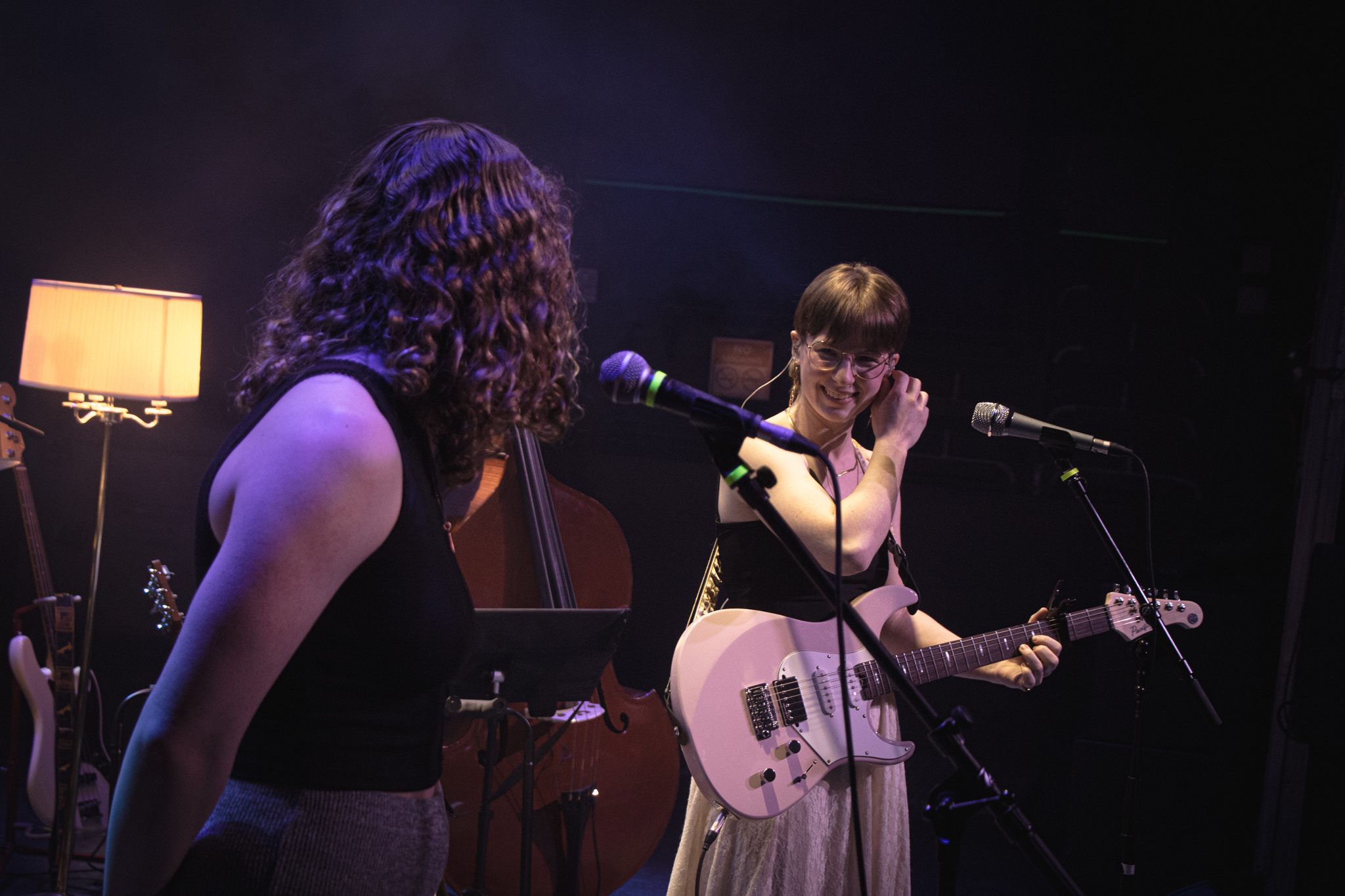 two women singing and playing guitars in front of a microphone