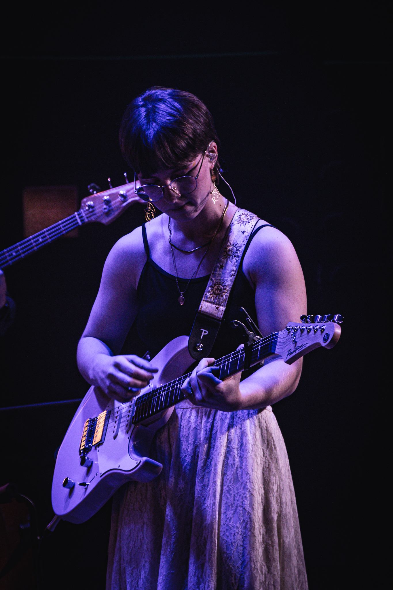 a woman in a dress playing a guitar on stage