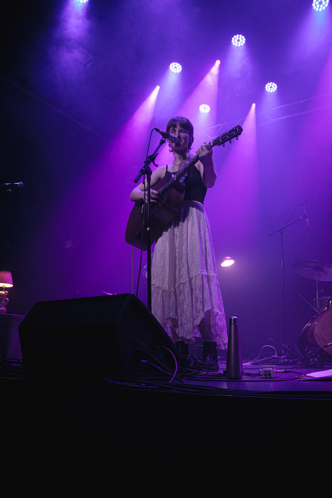 a woman playing an acoustic guitar on stage