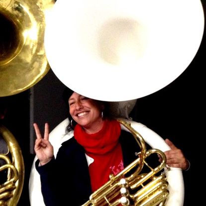a woman holding a tuba and making a peace sign