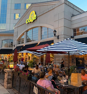 a group of people sitting outside a restaurant at dusk