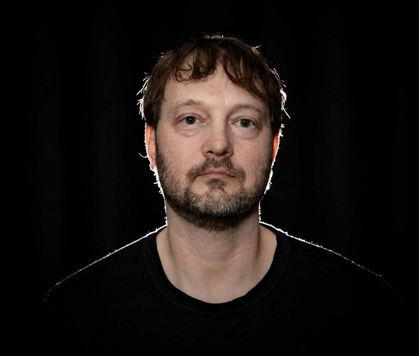a man in a black shirt is standing in front of a black background
