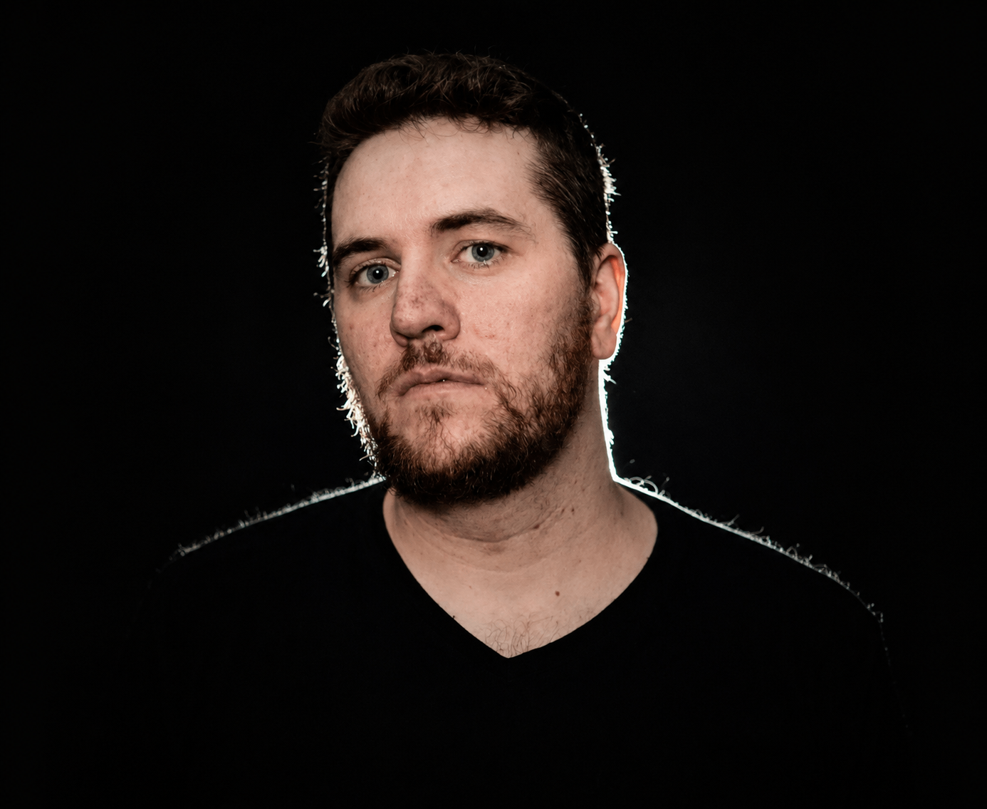 a man with a beard is standing in front of a black background