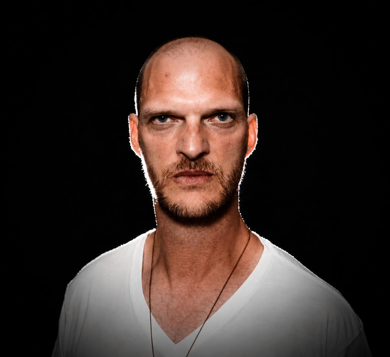 a bald man in a white shirt with a necklace
