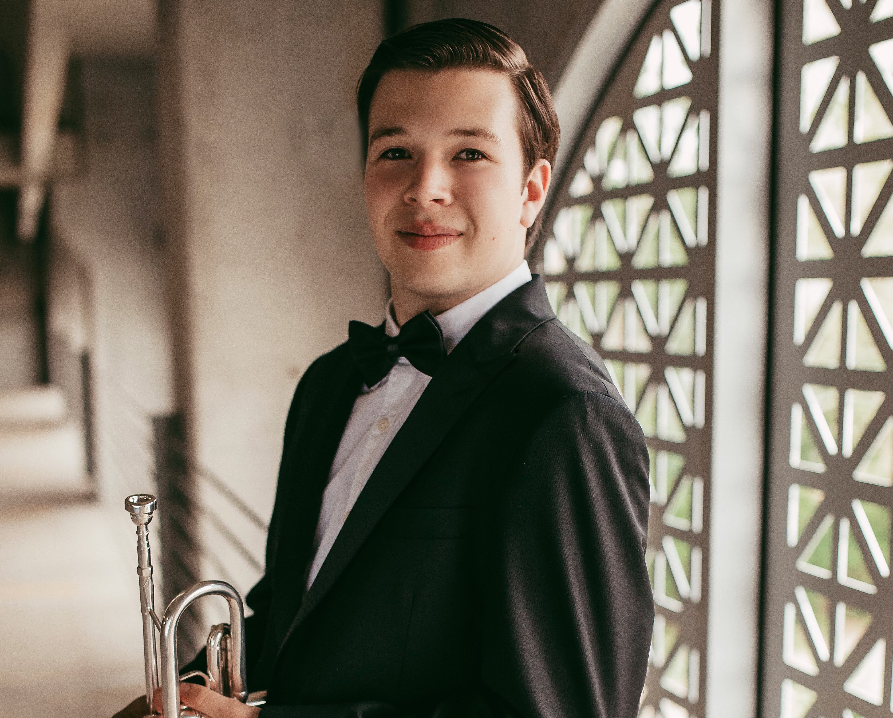 a young man in a tuxedo holding a trumpet