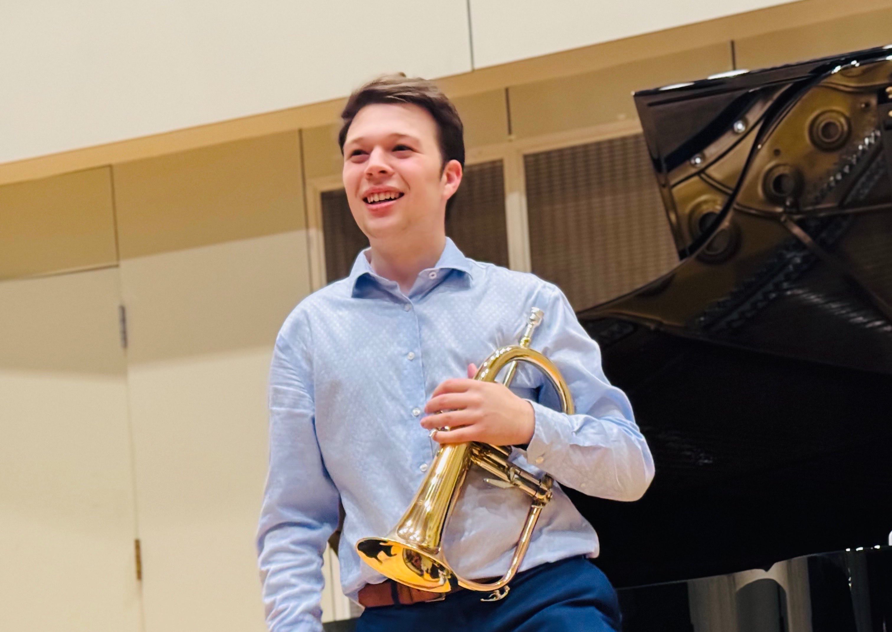 a young man holding a trumpet in front of a piano