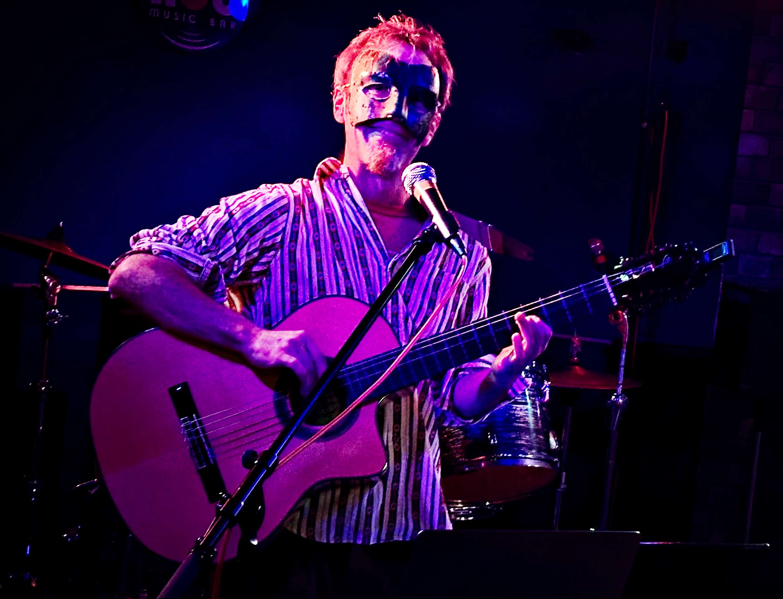 a man playing an acoustic guitar in front of a microphone