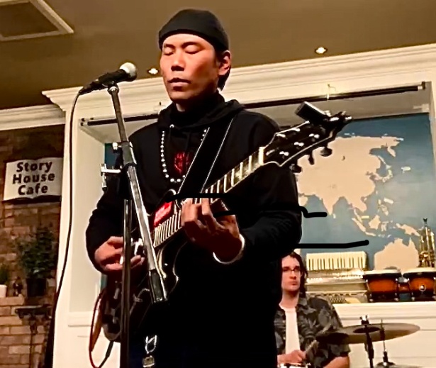 a man playing guitar in front of a microphone