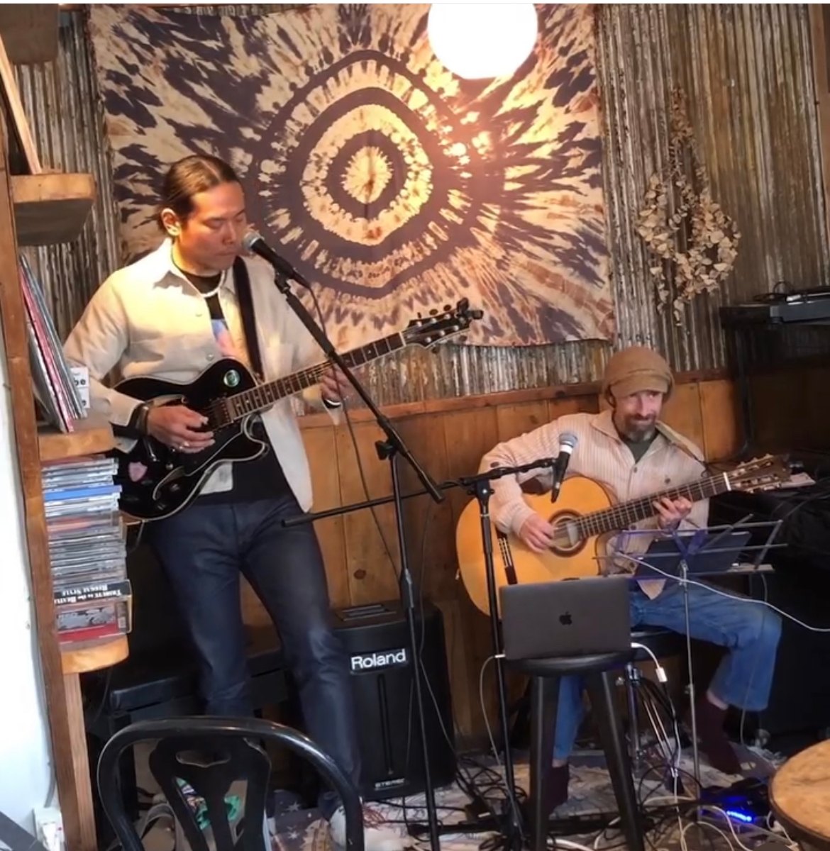 two men playing guitars in a coffee shop