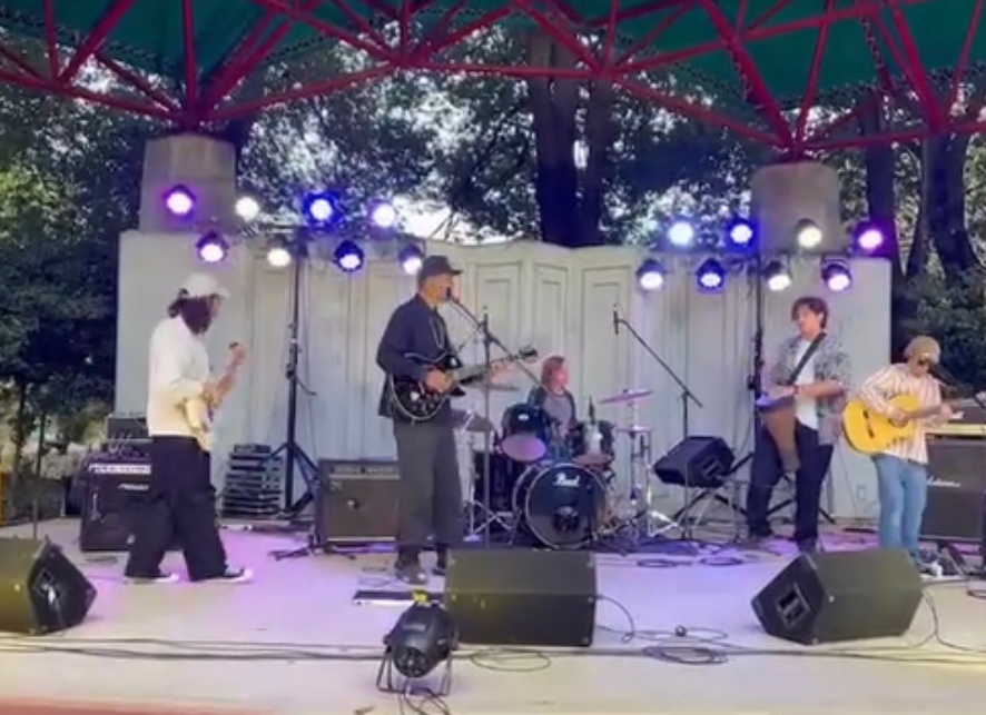 a group of people playing music on stage in a park