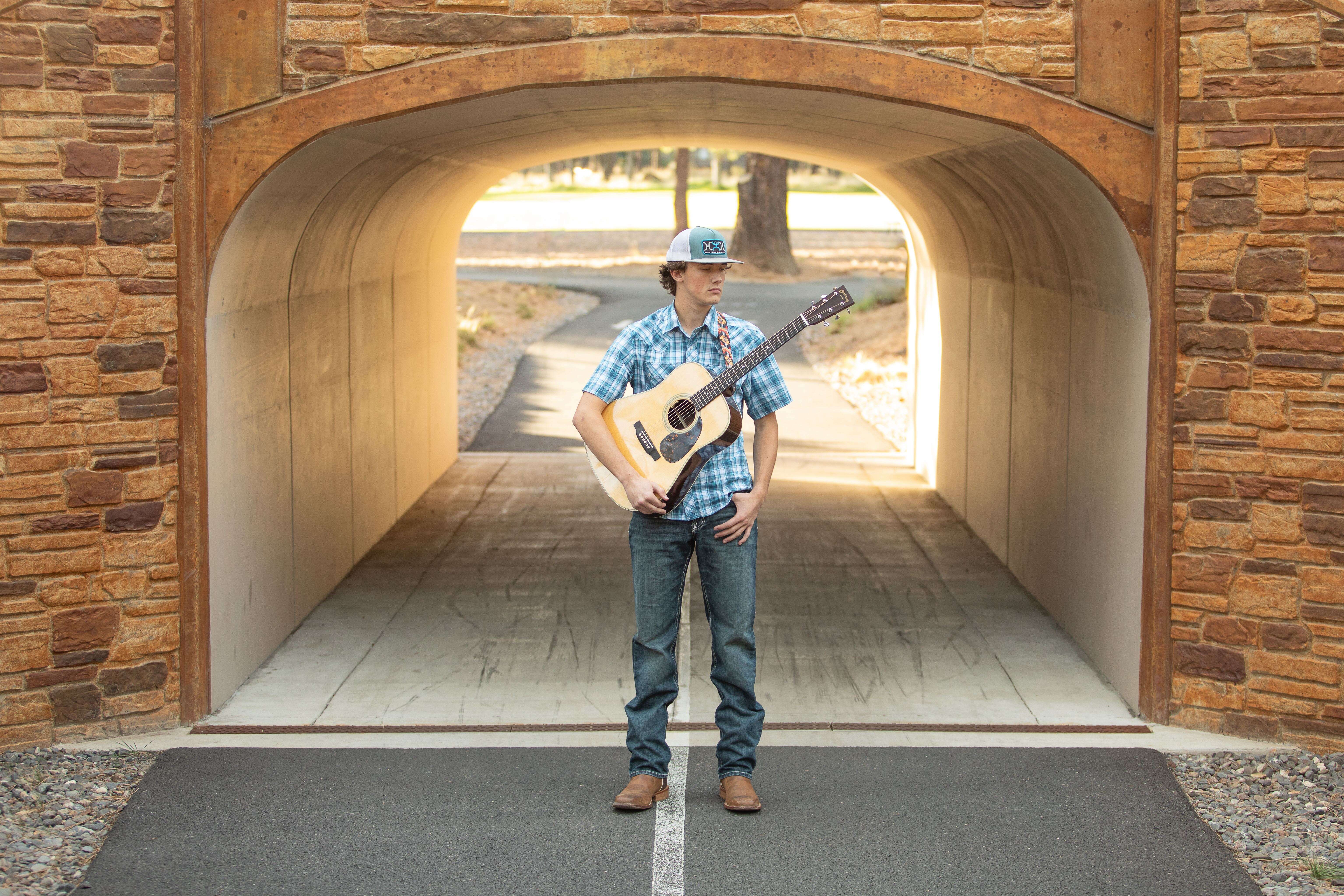 a man with a guitar standing in a tunnel