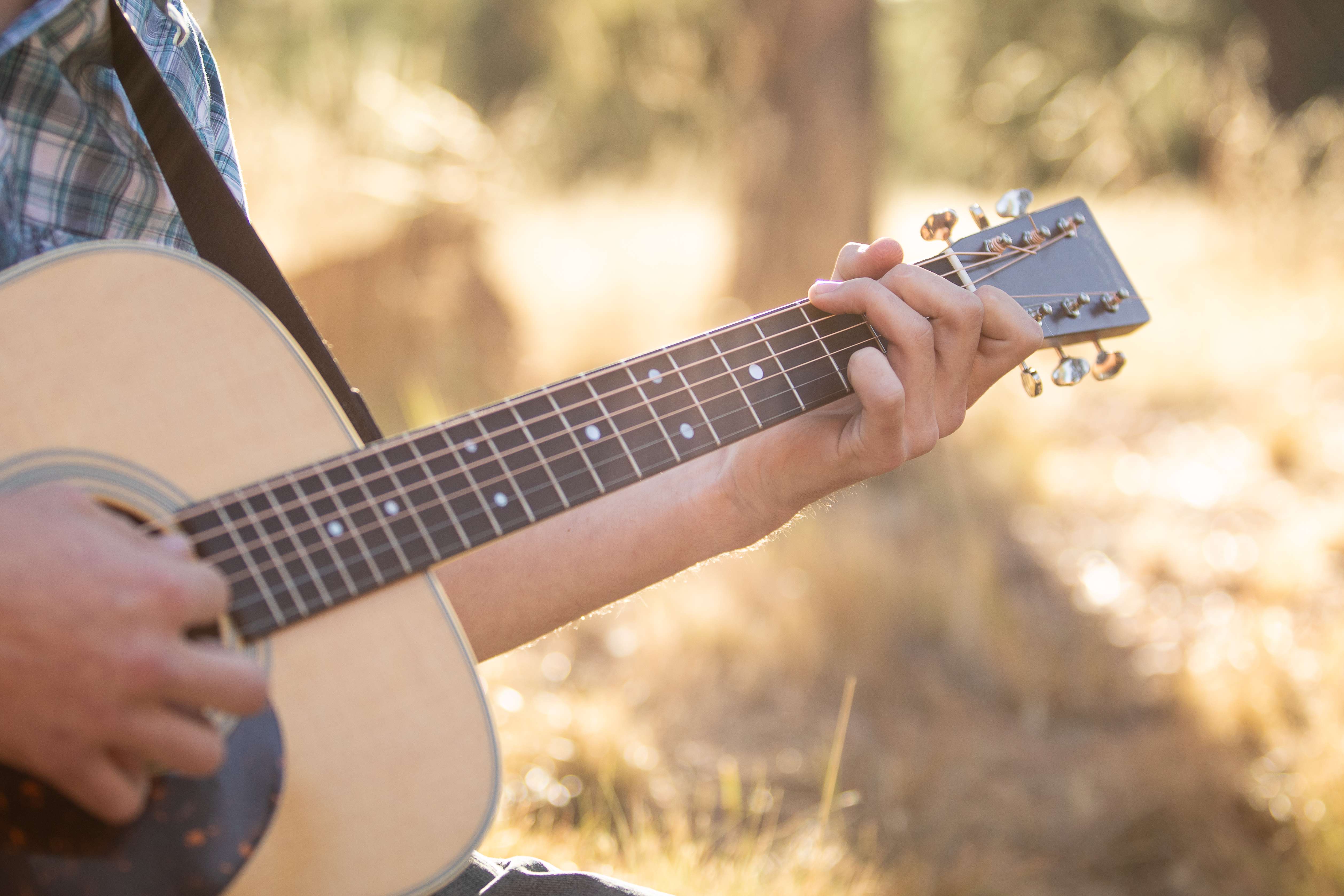 a man playing an acoustic guitar in a field