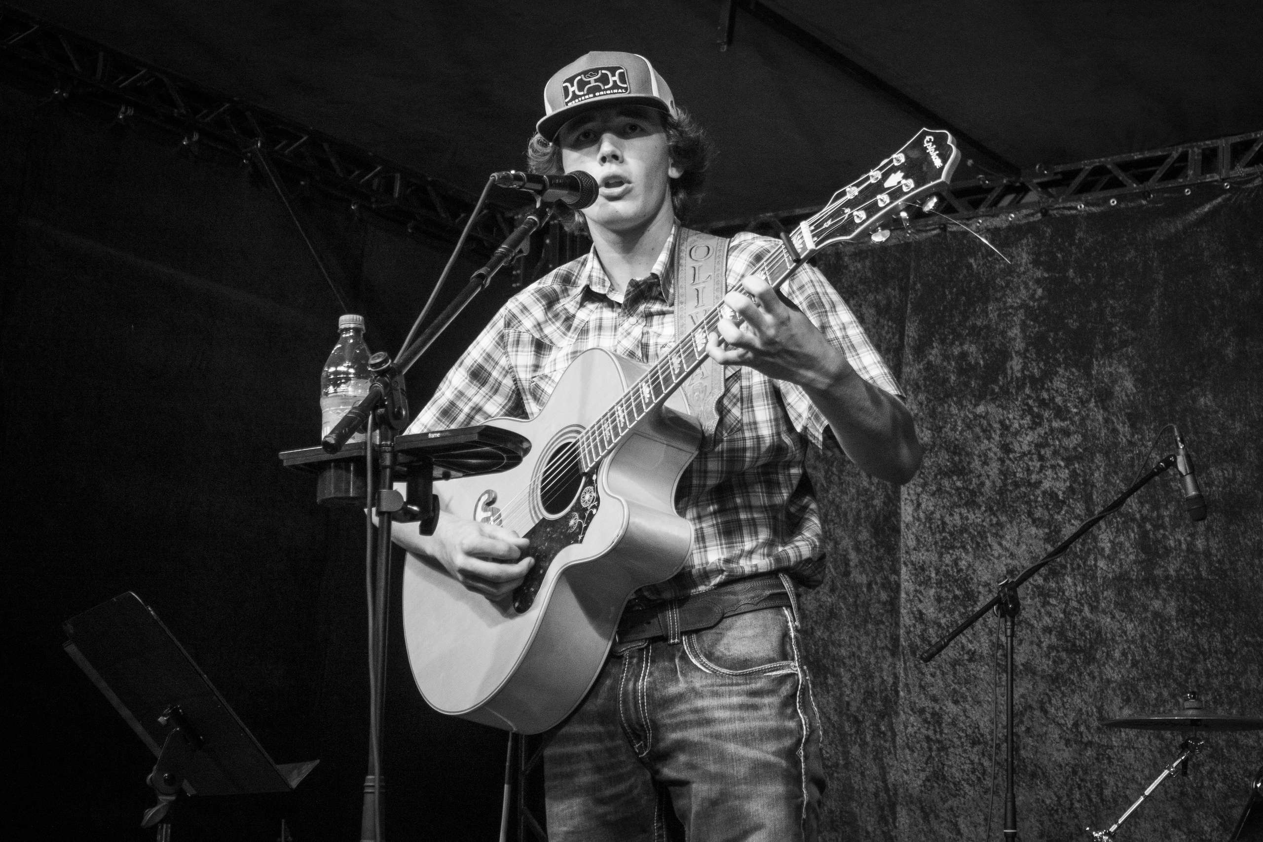 a man playing an acoustic guitar in front of a microphone